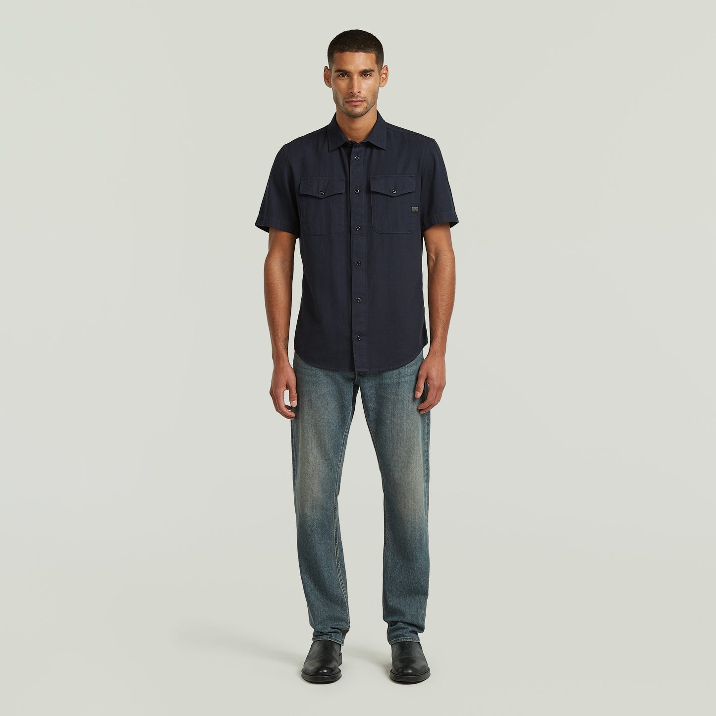 Hombre usando una camisa Marine slim azul con jeans, muestra el diseño ajustado y los bolsillos en el pecho.
