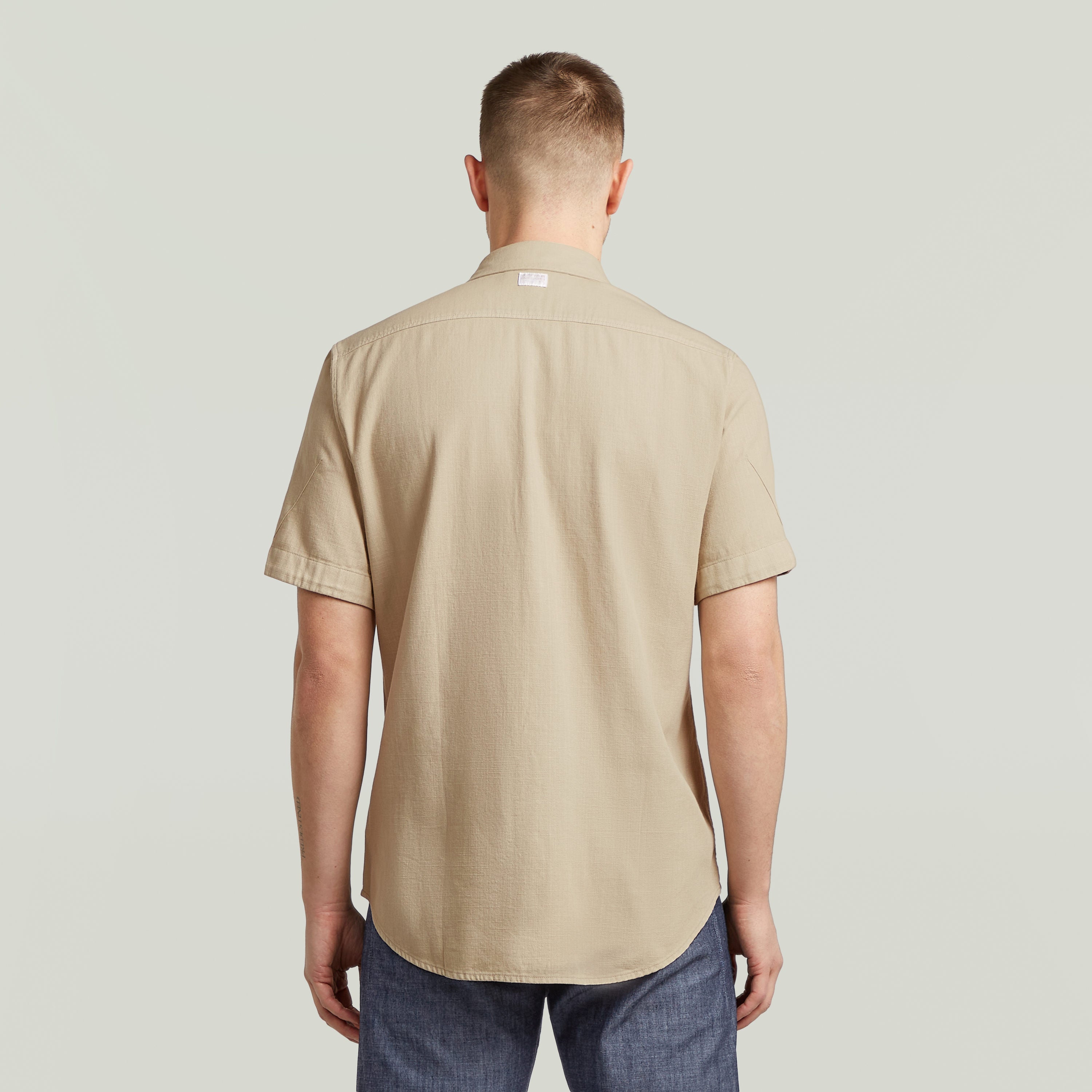 Camisa Marine Slim Fit beige vista trasera, corte ajustado y bajo redondeado.