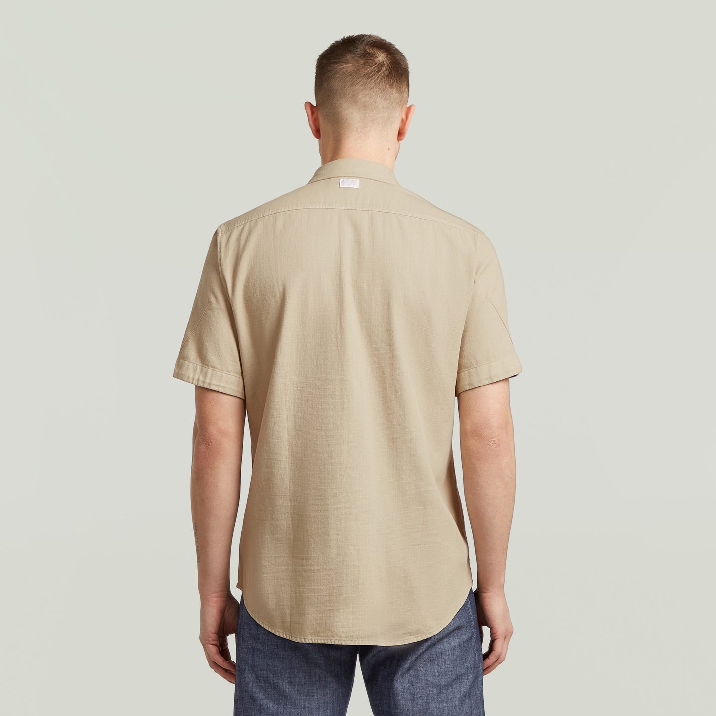 Camisa Marine Slim Fit beige vista trasera, corte ajustado y bajo redondeado.