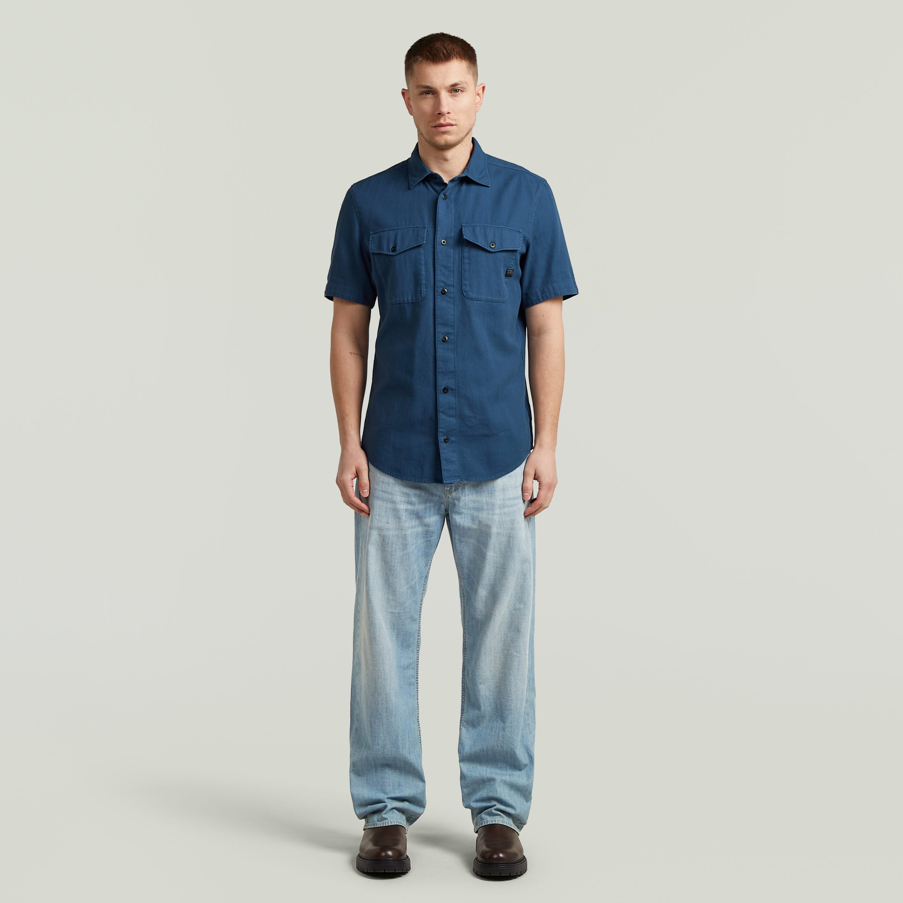 Modelo usando la camisa marine slim azul, con corte ajustado y bolsillos en el pecho.