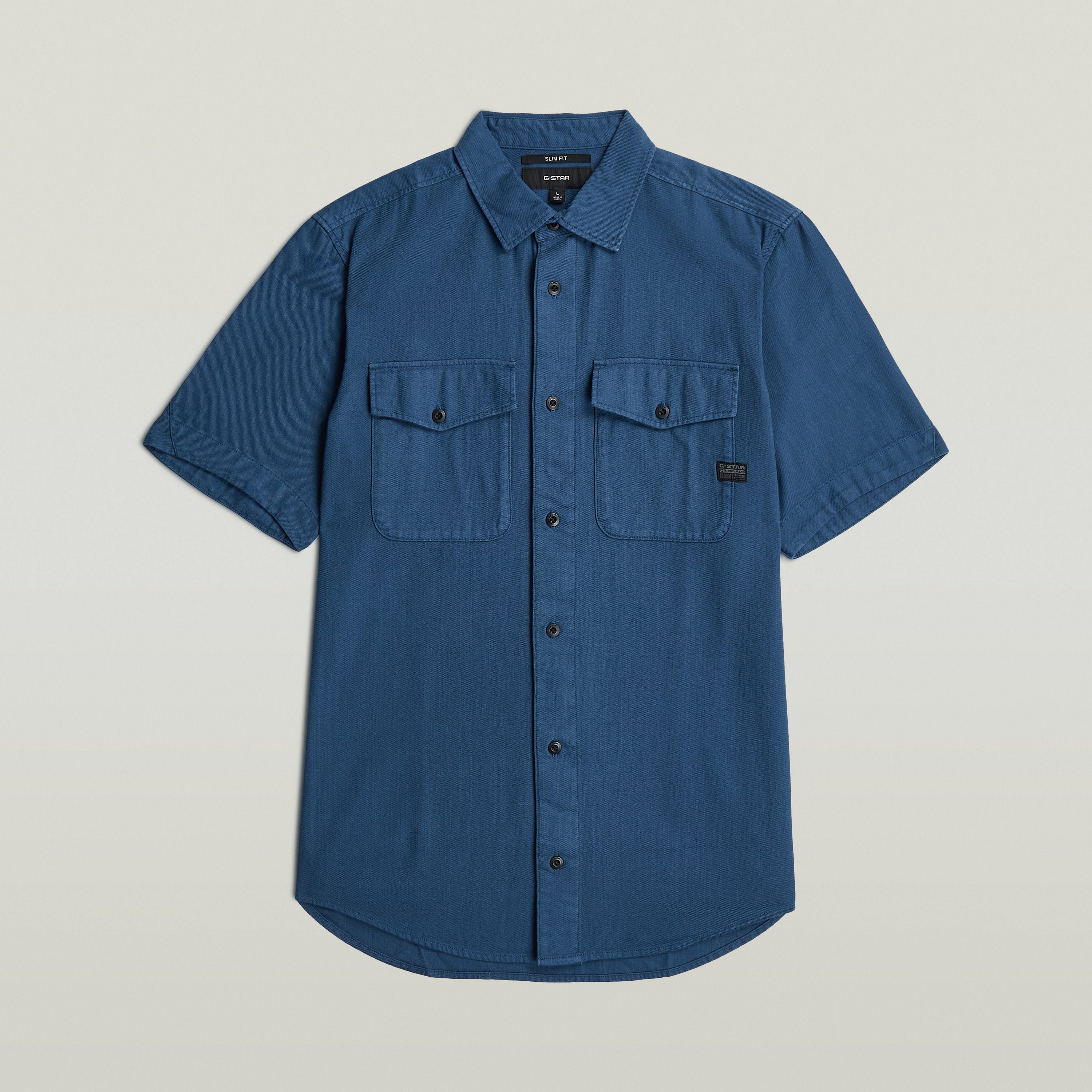 Camisa Marine Slim azul con corte ajustado, botones y bolsillos en el pecho, color azul intermedio.