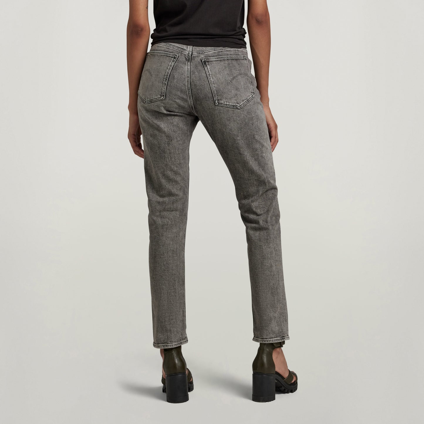 Mujer usando jeans Virjinya Slim de tiro alto y pernera ajustada, vista trasera en un fondo claro, alta moda.