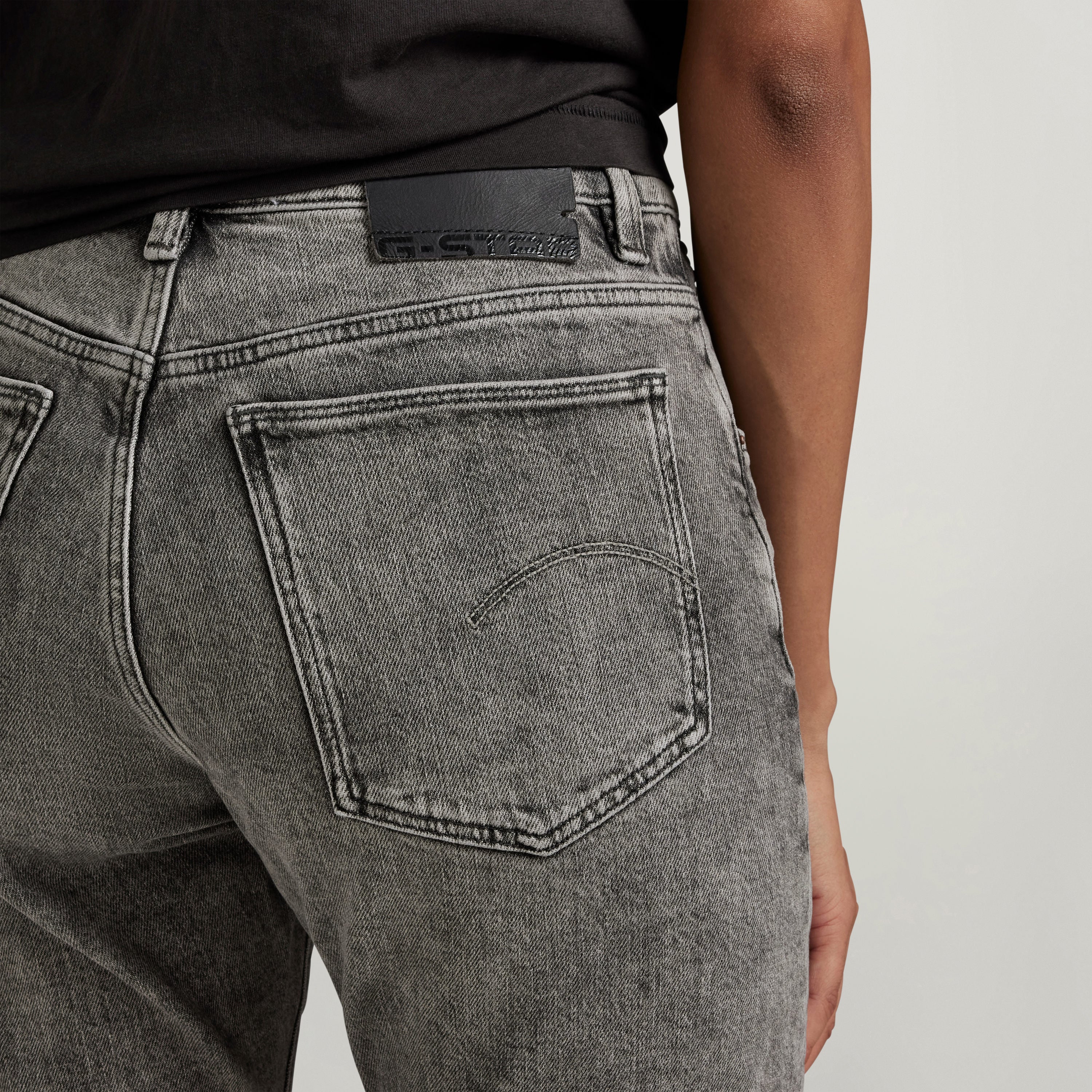 Detail of high-waisted slim jeans showing back pockets and denim texture