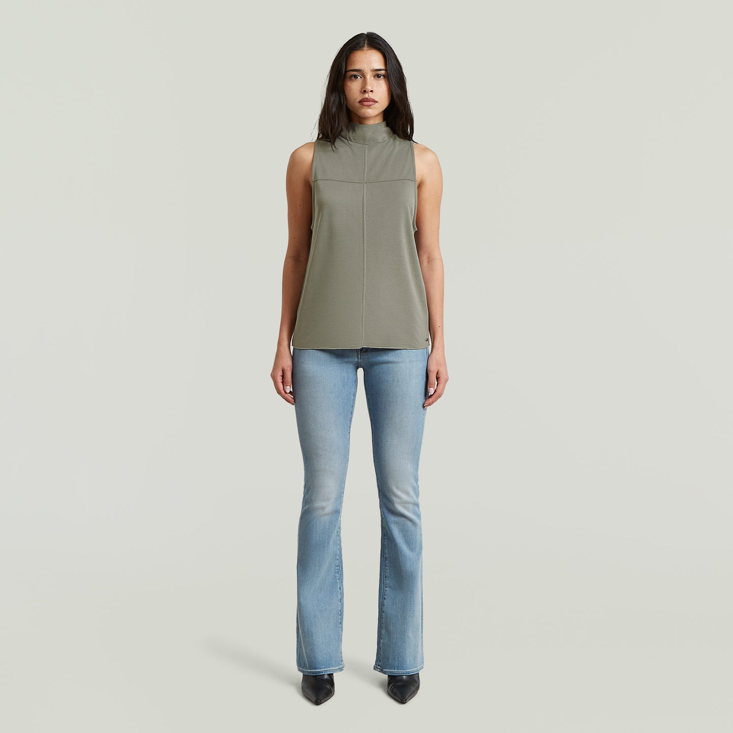 Mujer usando Jeans 3301 Flare inspirados en los 70, con blusa sin mangas y botas negras.