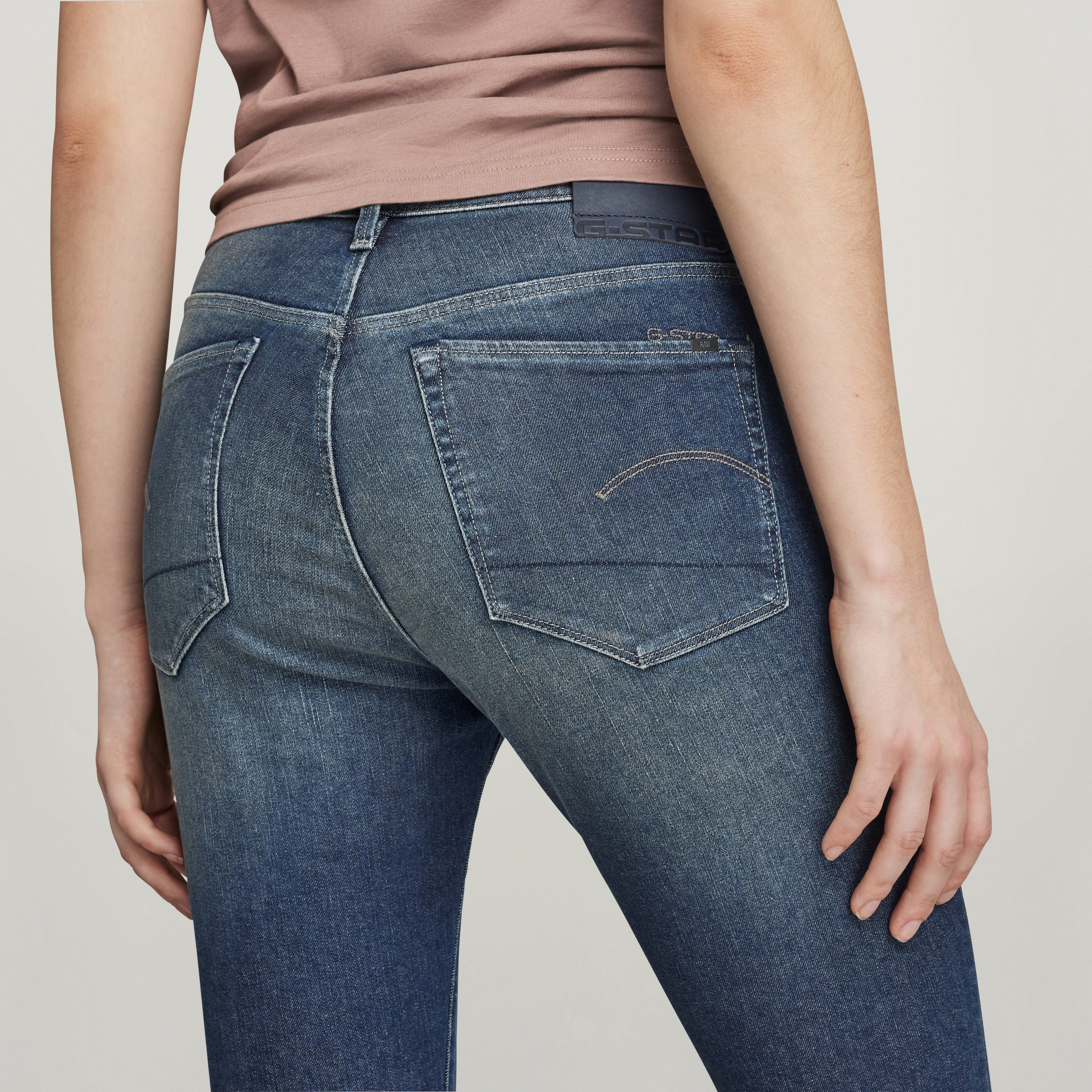 Mujer luciendo jeans 3301 skinny slit, vista trasera enfocando detalles de los bolsillos y corte ajustado.