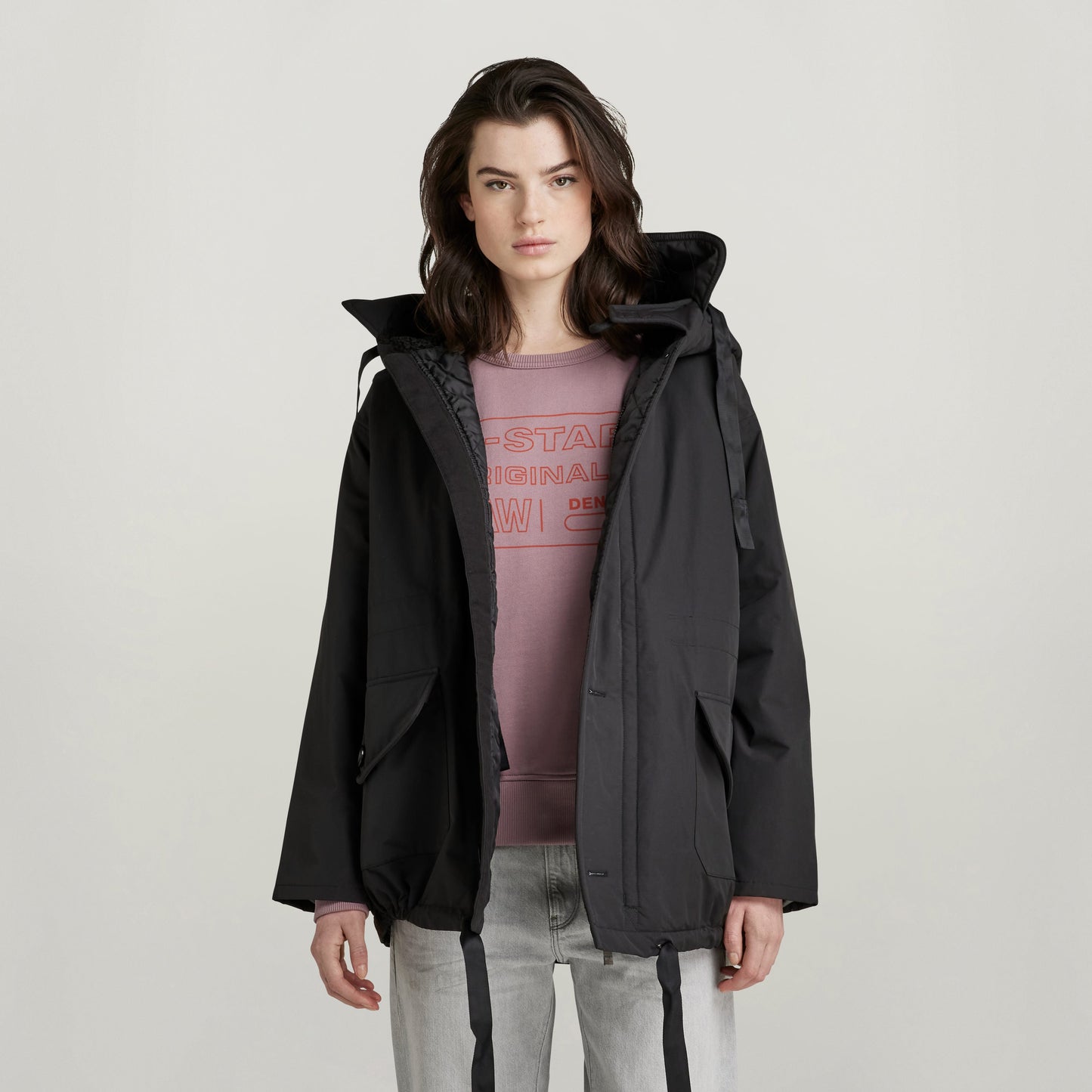 loose fit parka with hood in black, featuring a spacious hood and pockets, worn by a model.