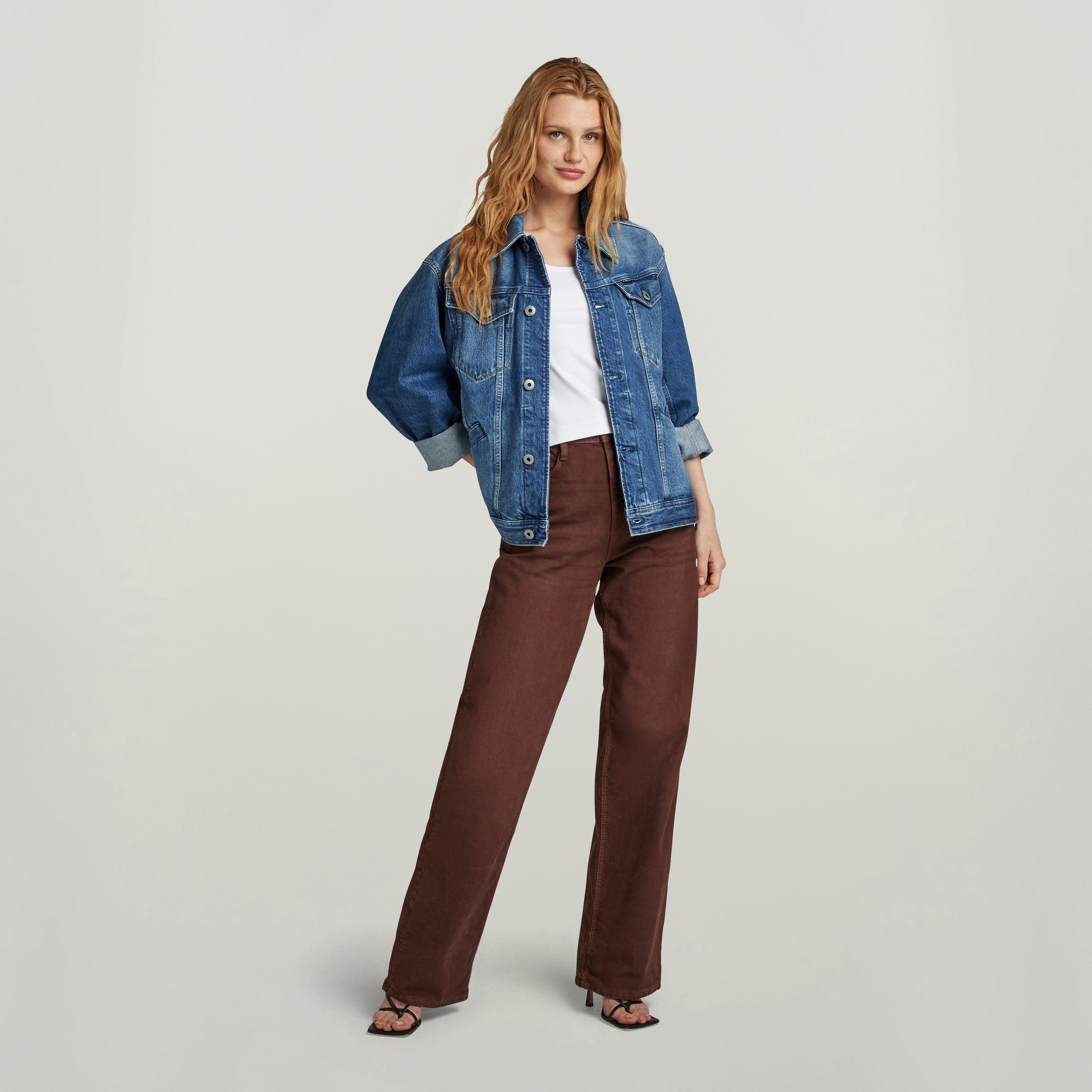 Modelo luciendo chaqueta unisex Flight Combat de denim, combinada con pantalones marrones y camiseta blanca.