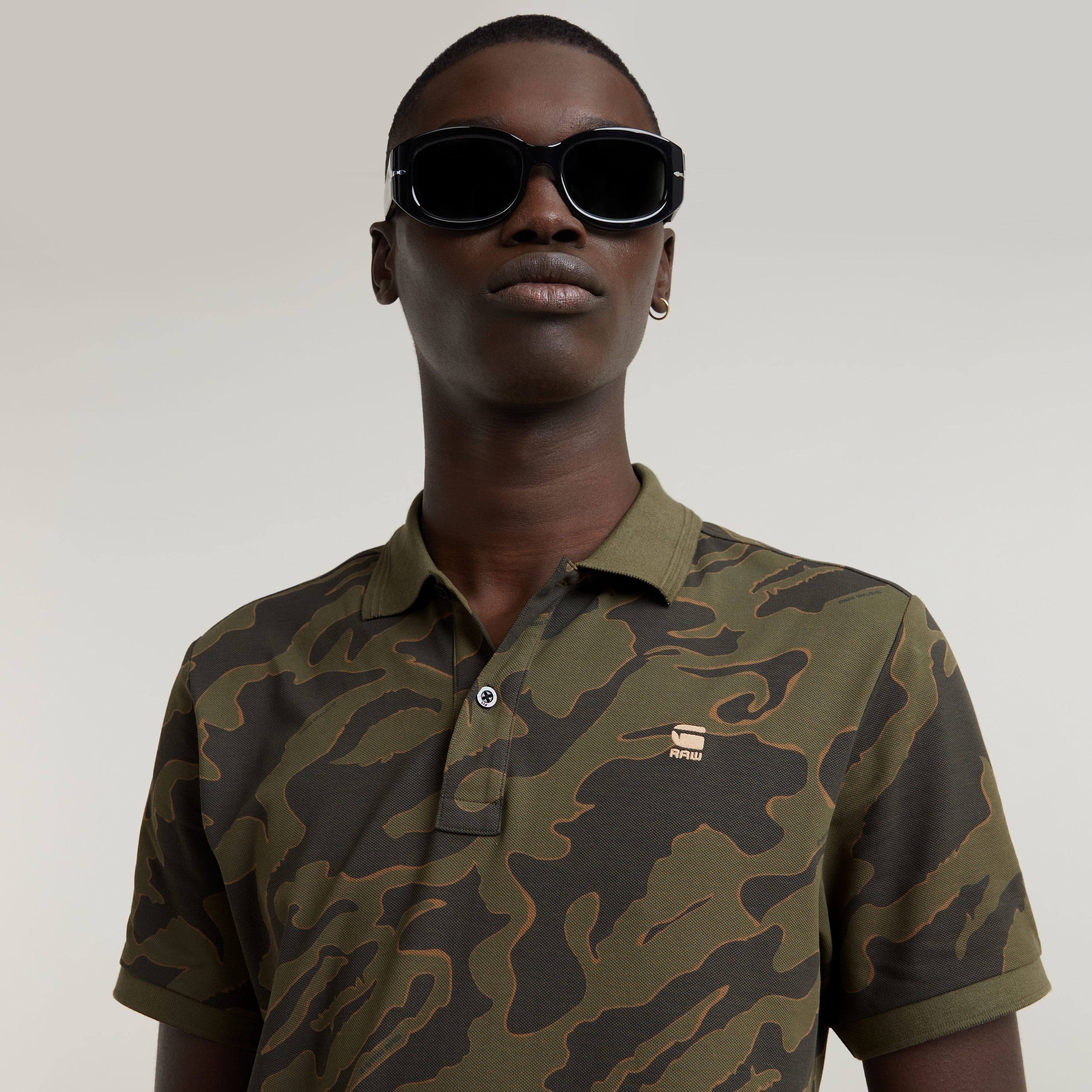 Model wearing slim stripe polo shirt with camouflage pattern and sunglasses.