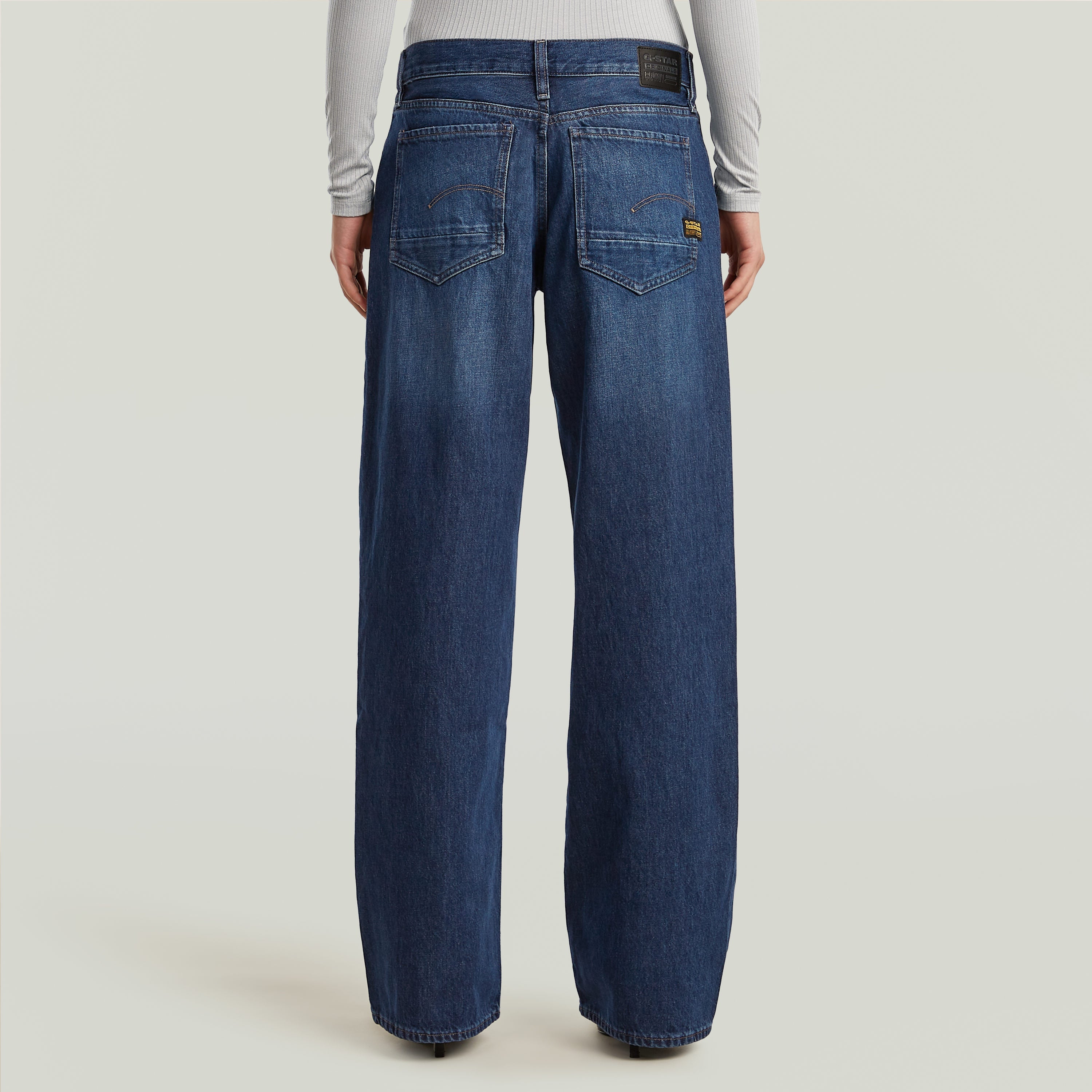 Mujer usando jeans Judee de cintura baja y corte holgado, vista trasera, ideales para el día a día, low waist loose jeans.