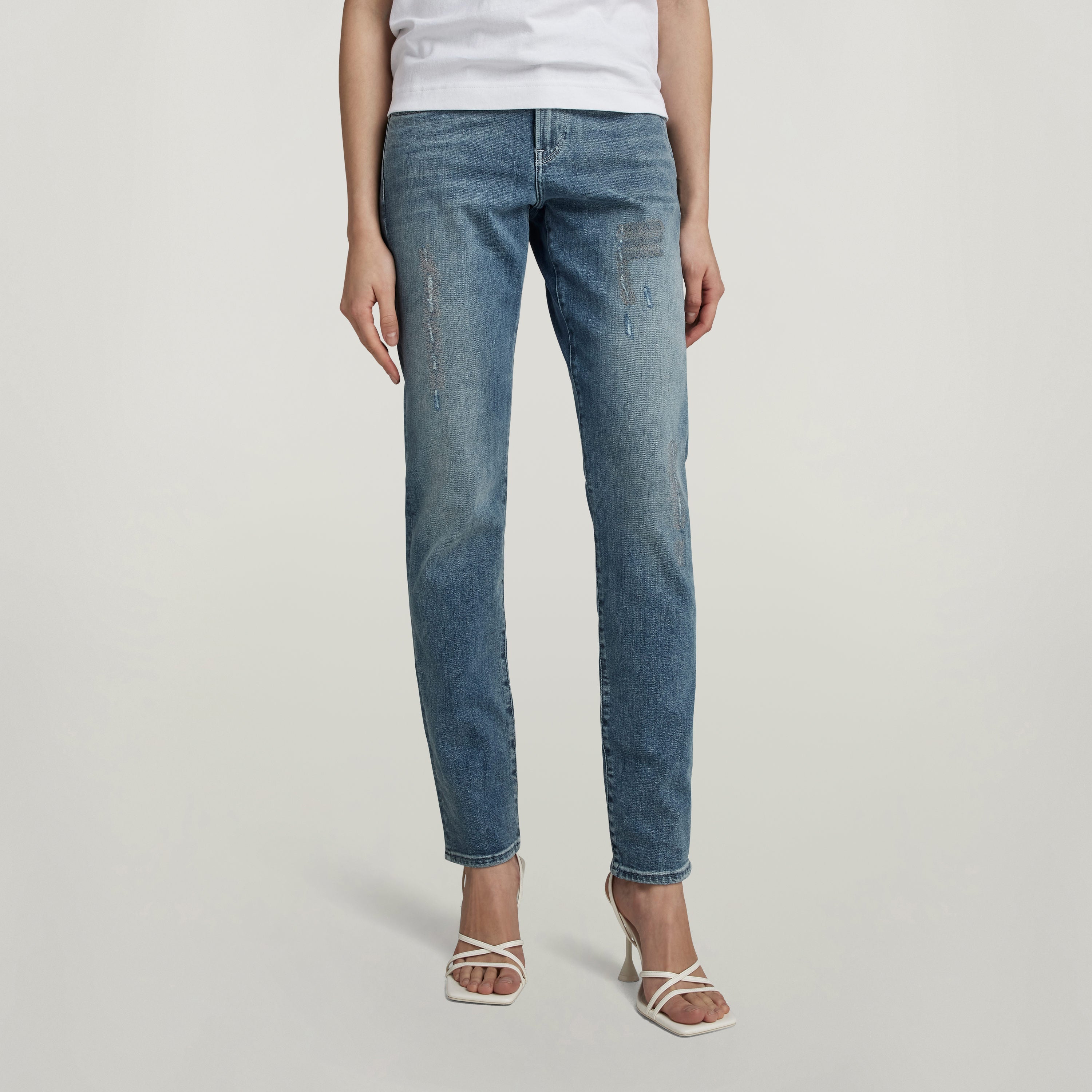 Mujer usando jeans Ace Slim de corte ajustado y bajo en color azul, mostrando detalles de diseño y estilo.