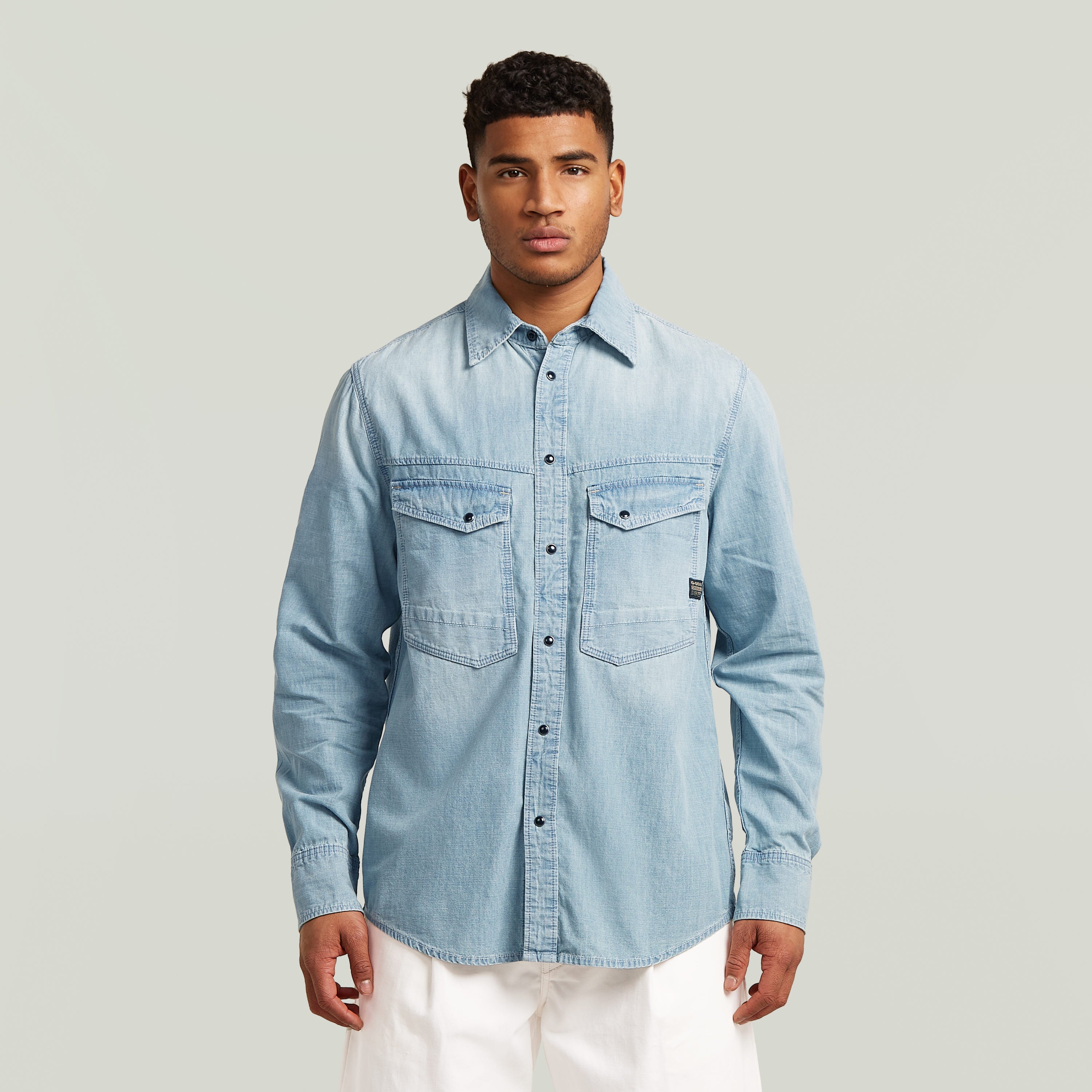 Camisa de manga larga Dakota en denim azul claro con cierre de botones y cuello clásico, modelo masculino.
