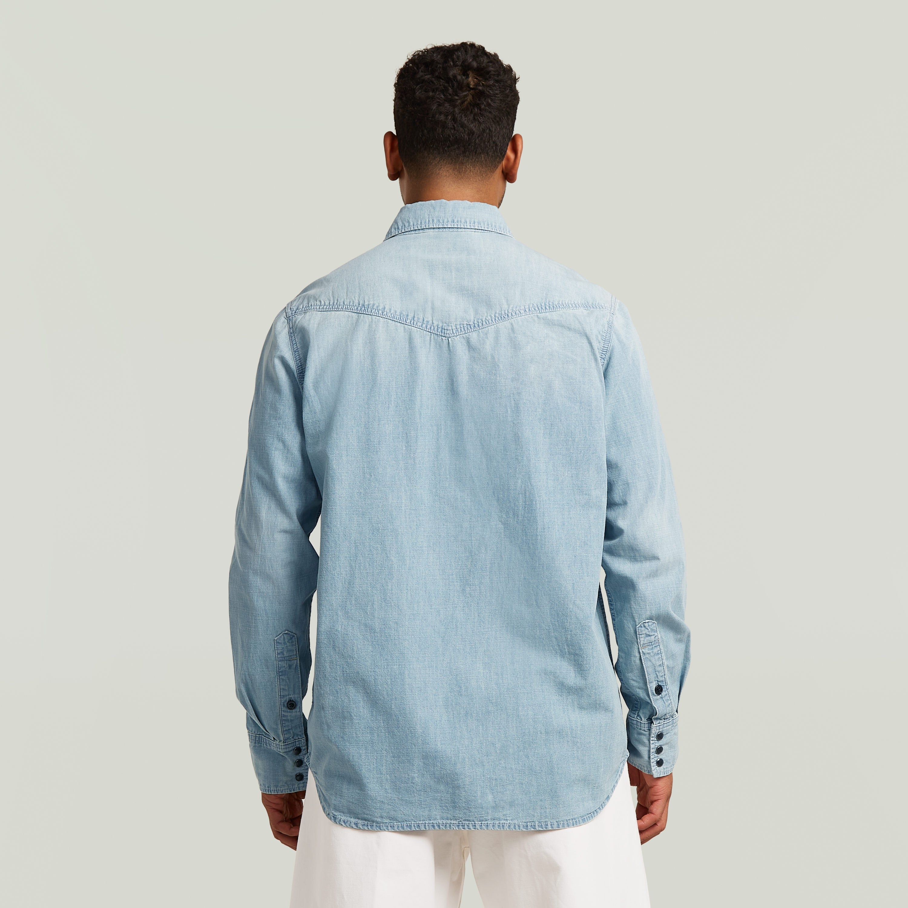 Hombre de espaldas usando camisa de manga larga Dakota de denim azul claro.