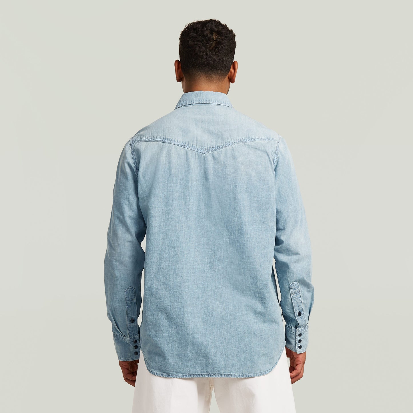 Hombre de espaldas usando camisa de manga larga Dakota de denim azul claro.