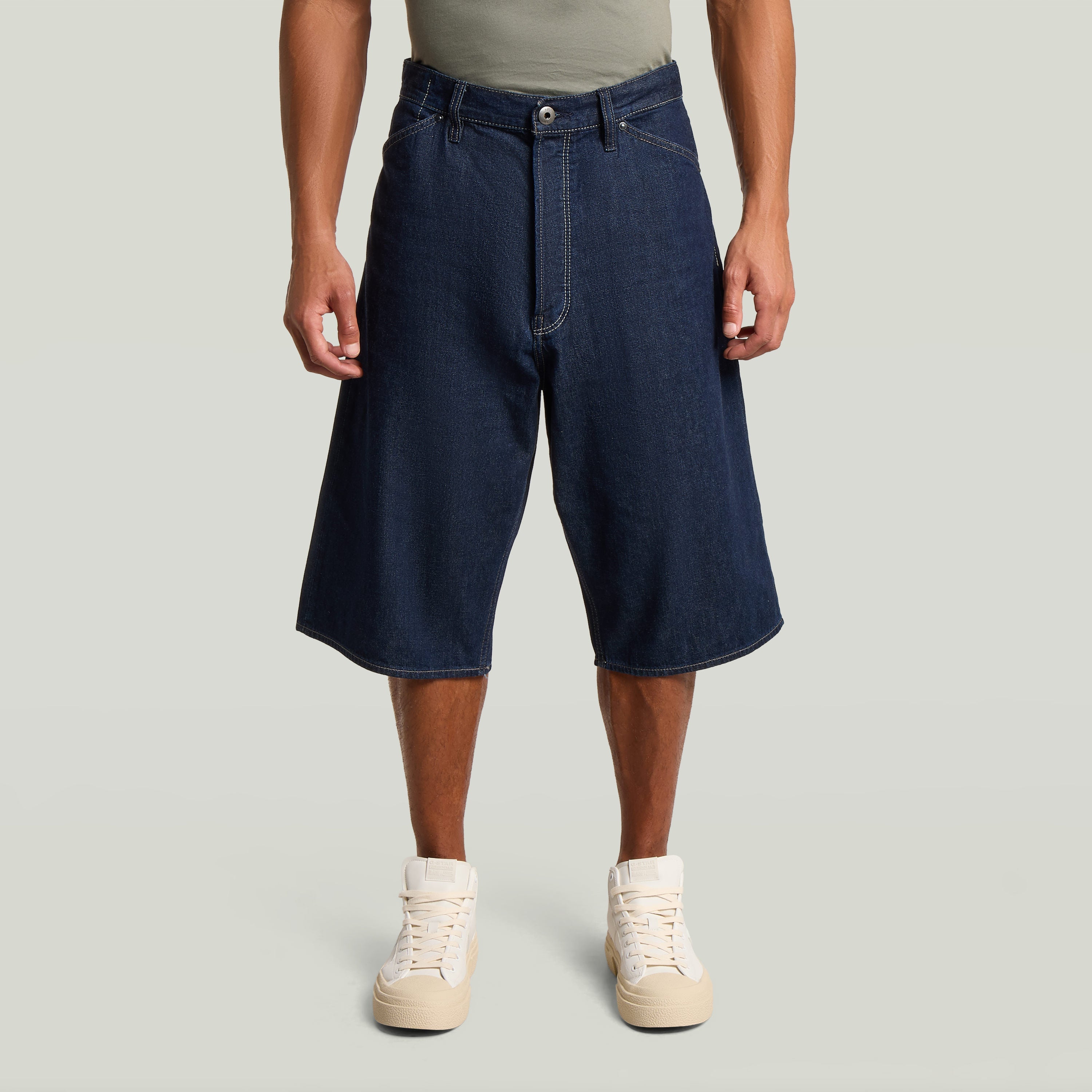 Hombre usando jorts de corte relajado con talle medio, color azul oscuro y cierre abotonado.