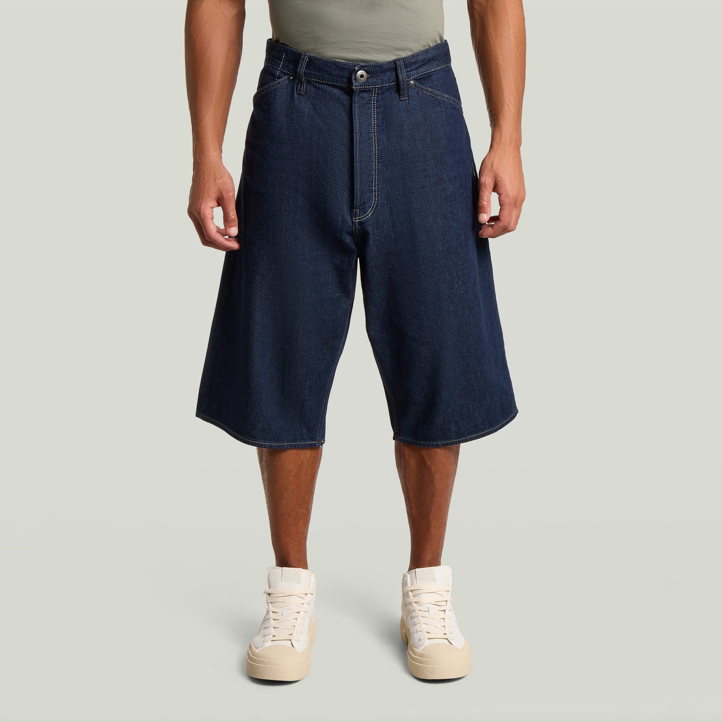 Hombre usando jorts de corte relajado con talle medio, color azul oscuro y cierre abotonado.
