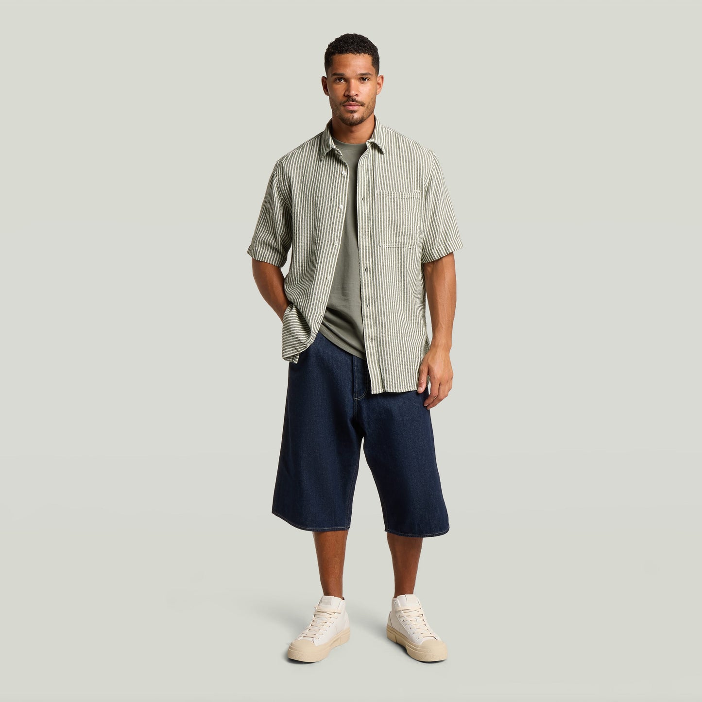 Model wearing relaxed fit jorts with a striped shirt and casual sneakers on a neutral background.