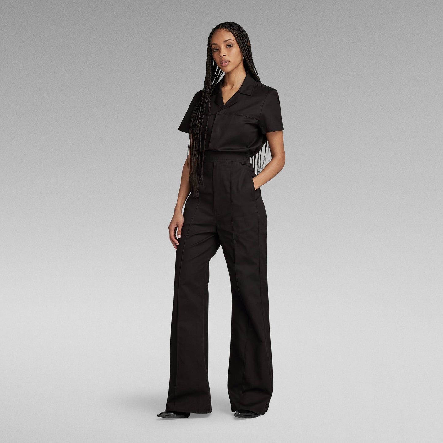 Mujer vestida con un enterizo wide leg denim jumpsuit negro, mostrando un corte holgado y cintura elástica.