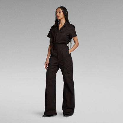 Mujer con enterizo wide leg denim jumpsuit negro, corte holgado y cintura elástica, luciendo estilo moderno.