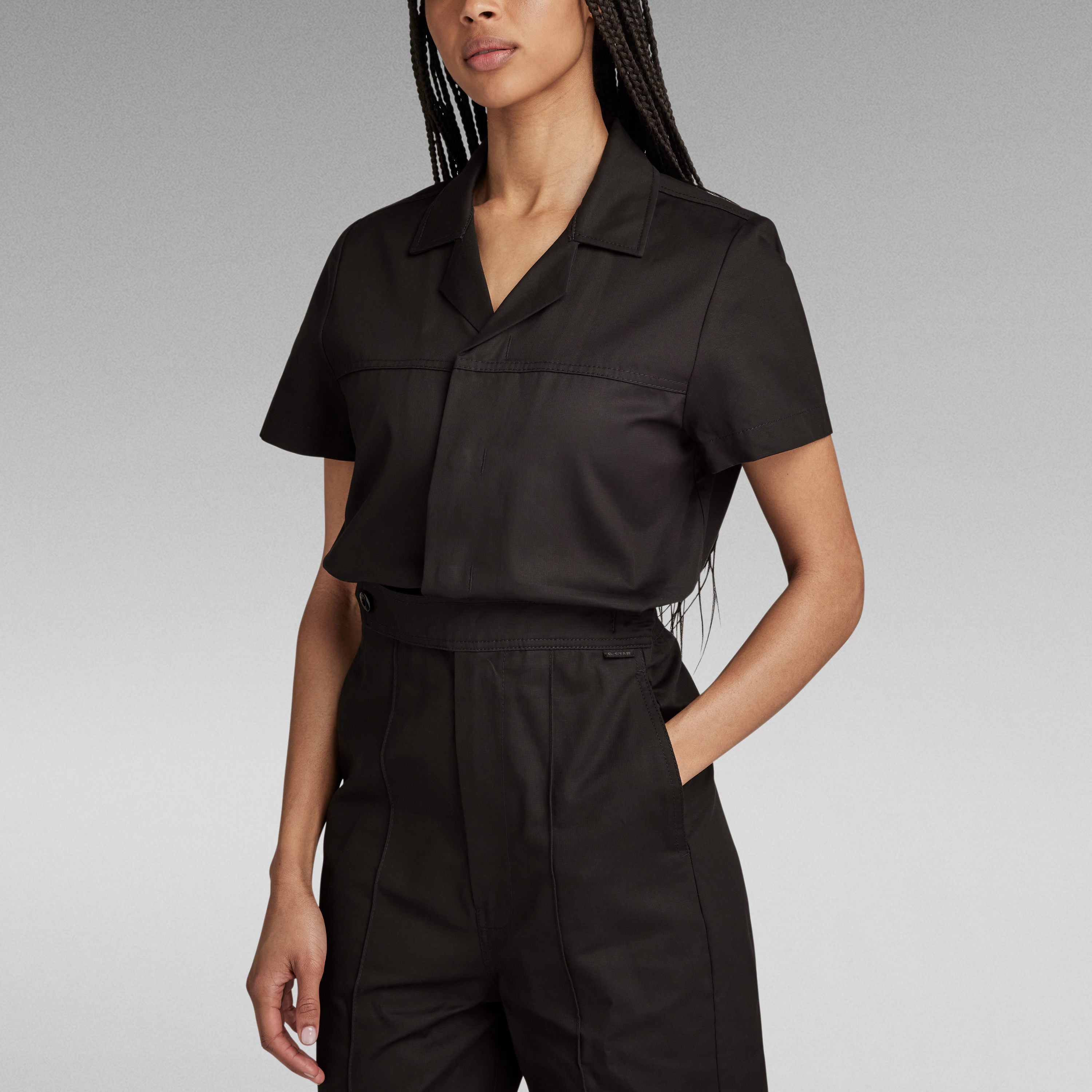 Mujer usando un enterizo wide leg denim jumpsuit negro, con corte holgado y detalles de diseño.