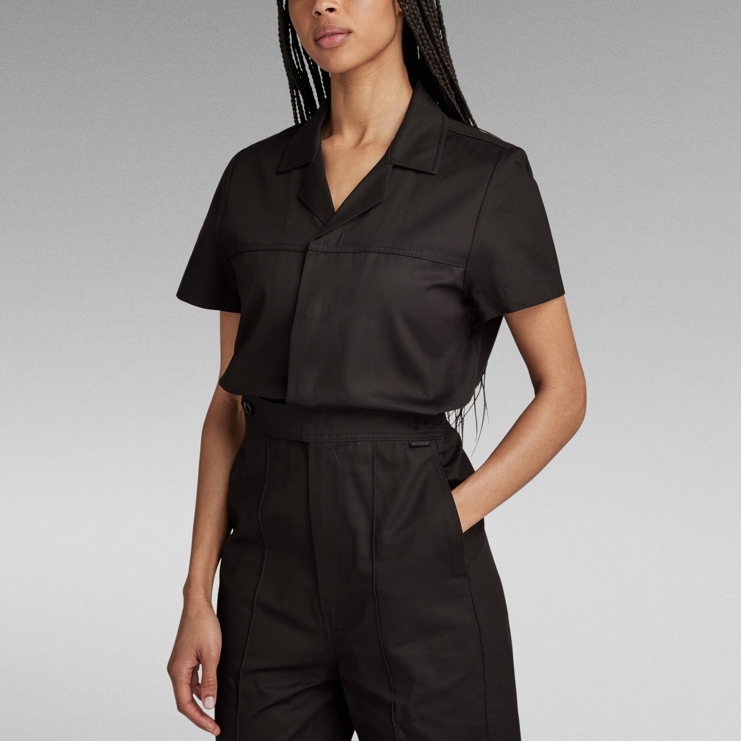 Mujer usando un enterizo wide leg denim jumpsuit negro, con corte holgado y detalles de diseño.