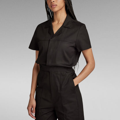 Mujer usando un enterizo wide leg denim jumpsuit negro, con corte holgado y detalles de diseño.