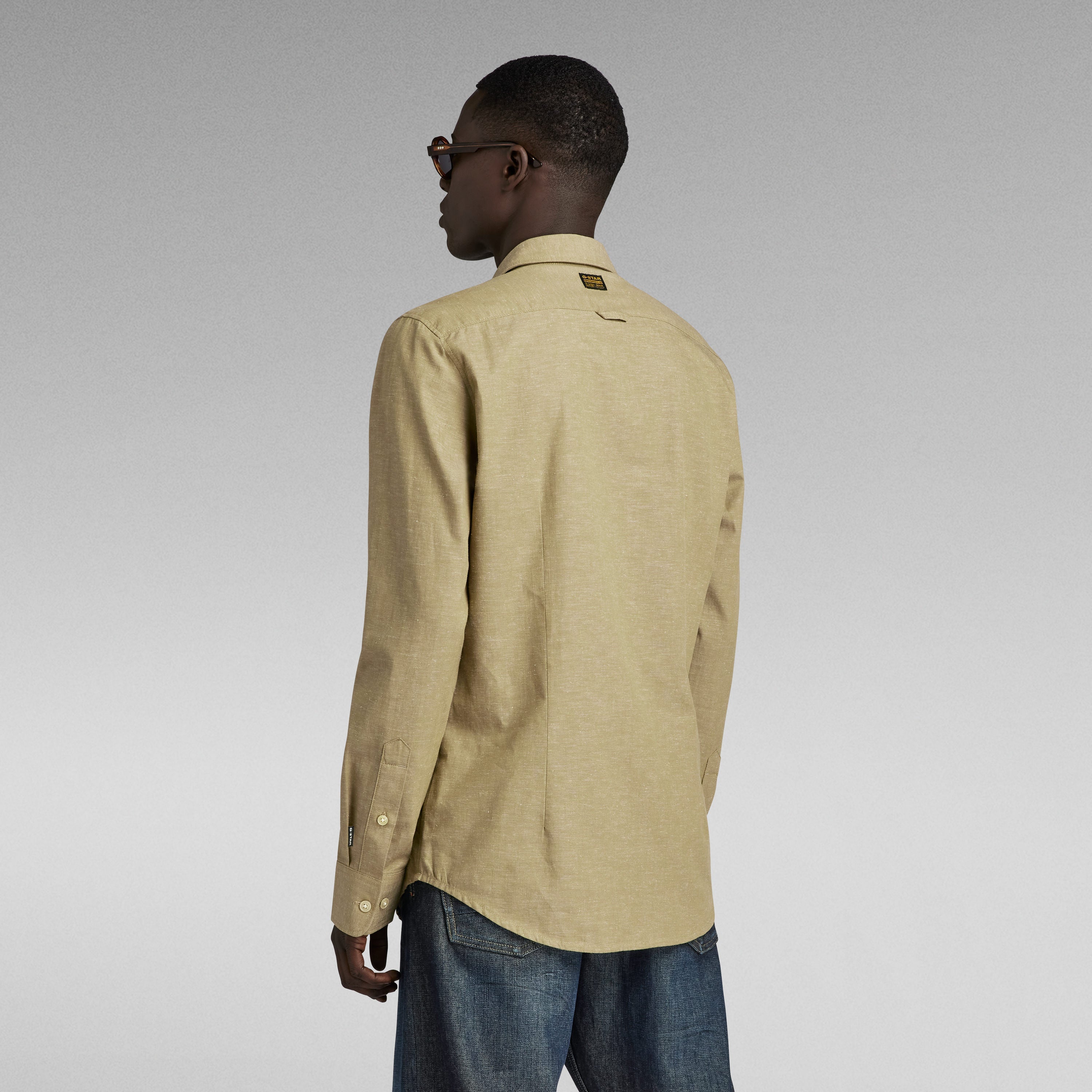 Modelo de espaldas usando la camisa bristum 2.0 slim color beige con detalles de diseño elegante.