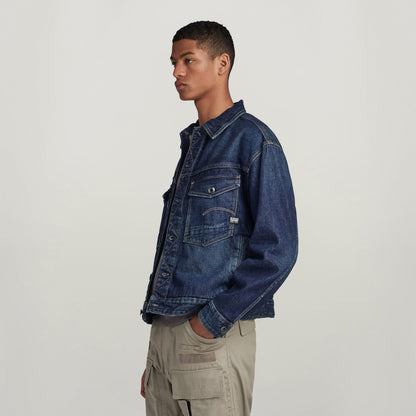 Hombre usando chaqueta denim Dakota de corte recto con bolsillos y cierre de botón en fondo neutral.