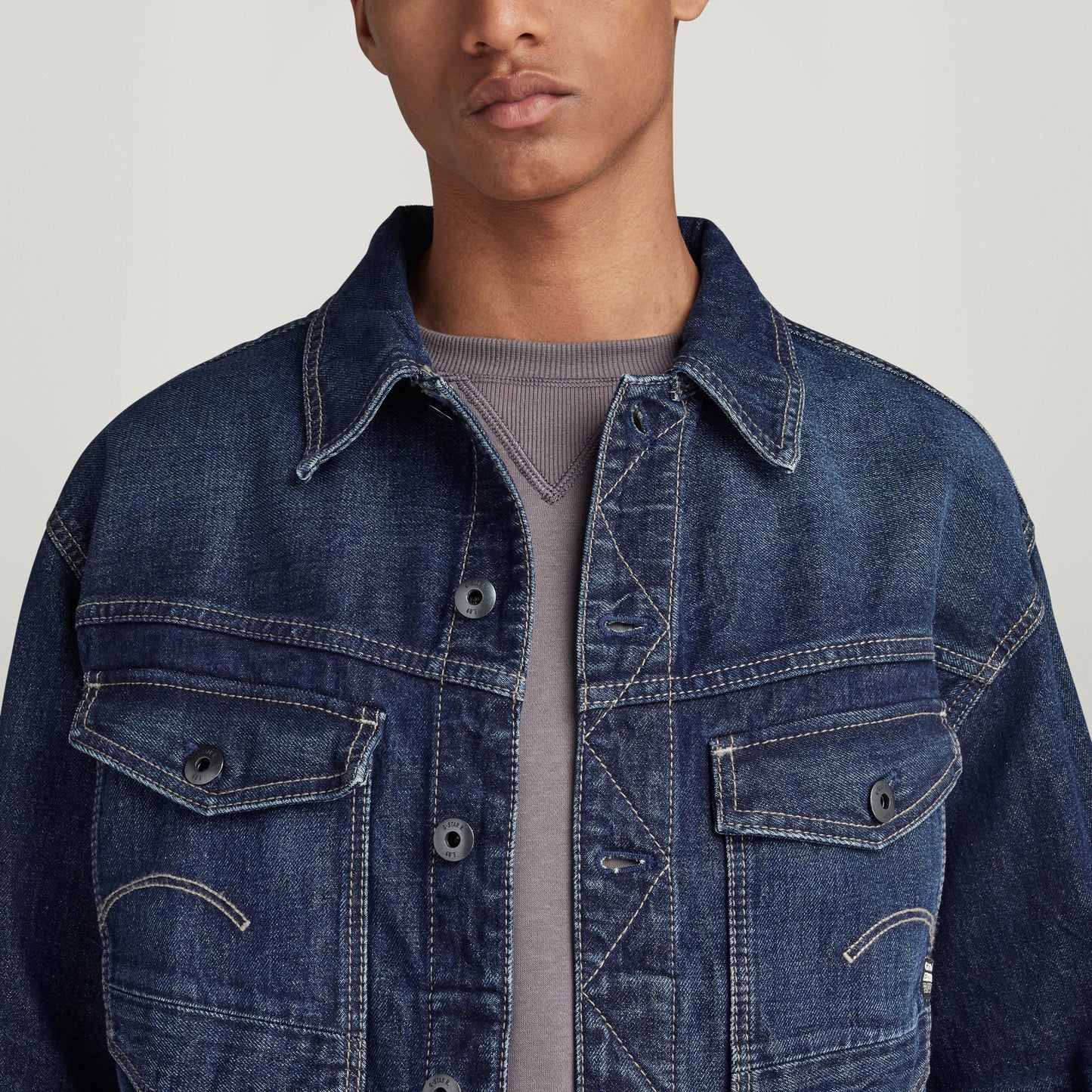 Chaqueta denim Dakota en modelo masculino con detalles de bolsillo y cierre de botón, fondo claro.