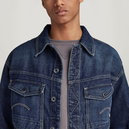 Chaqueta denim Dakota en modelo masculino con detalles de bolsillo y cierre de botón, fondo claro.