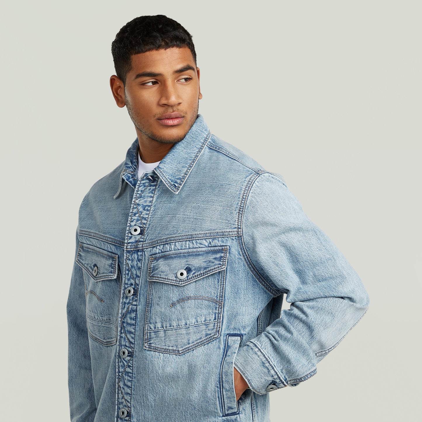 Modelo vistiendo chaqueta denim Dakota con corte recto y bolsillos, vista lateral, fondo neutro.