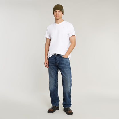 Modelo usando jeans Dakota Regular Straight para hombres con camiseta blanca y gorro, estilo casual.