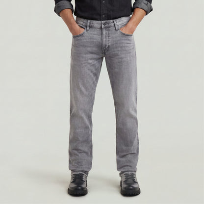 Hombre usando Jeans Mosa Straight en color gris con camisa negra y botas, mostrando un estilo casual y moderno.