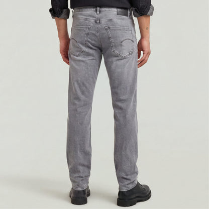 Hombre vistiendo Mosa straight jeans, vista trasera, diseño clásico con ajuste medio y pierna estrecha en color gris.