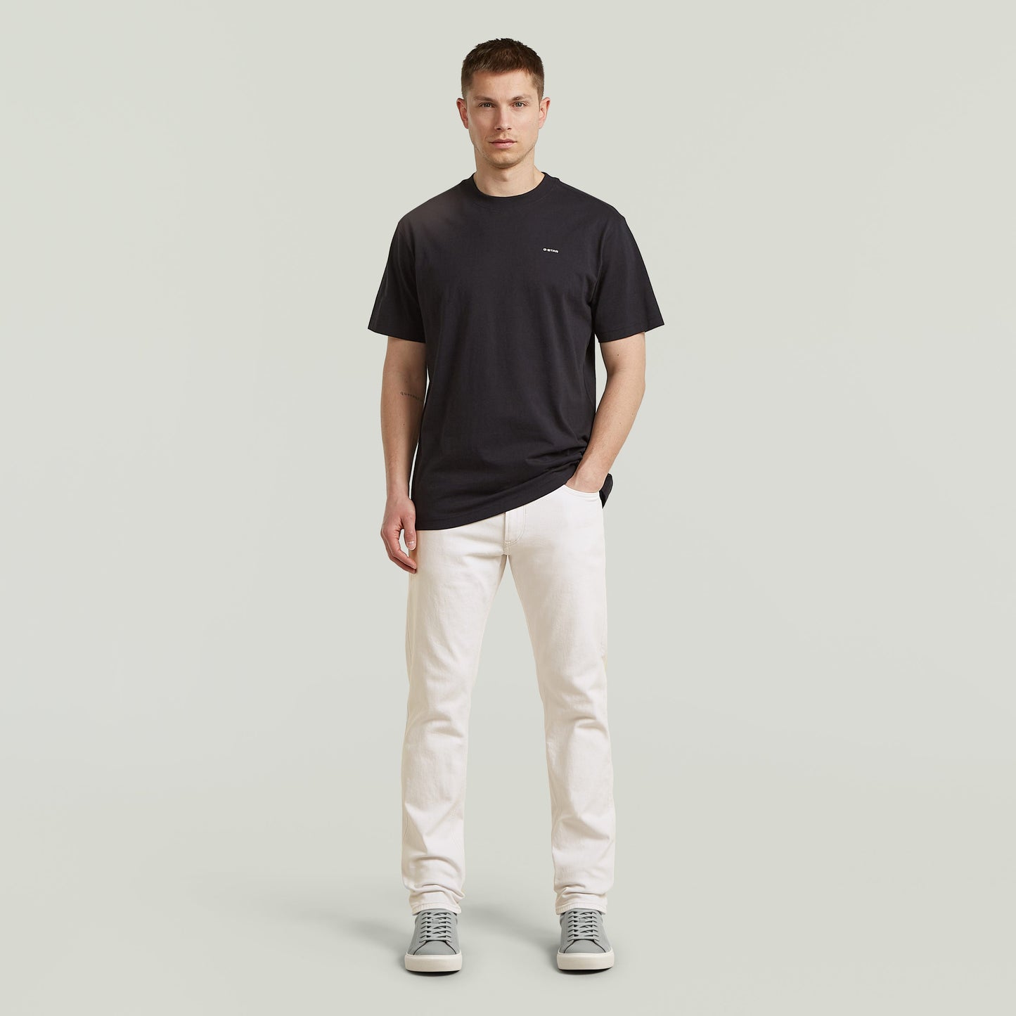 Modelo masculino vistiendo Mosa straight jeans en color blanco con camiseta negra y zapatillas grises.