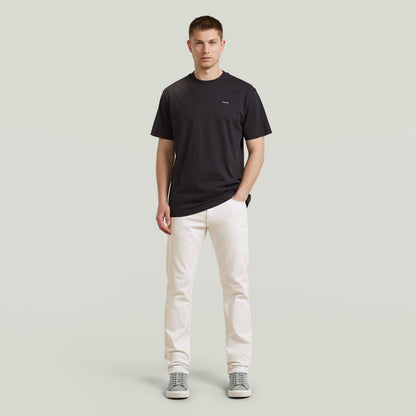 Modelo masculino vistiendo Mosa straight jeans en color blanco con camiseta negra y zapatillas grises.
