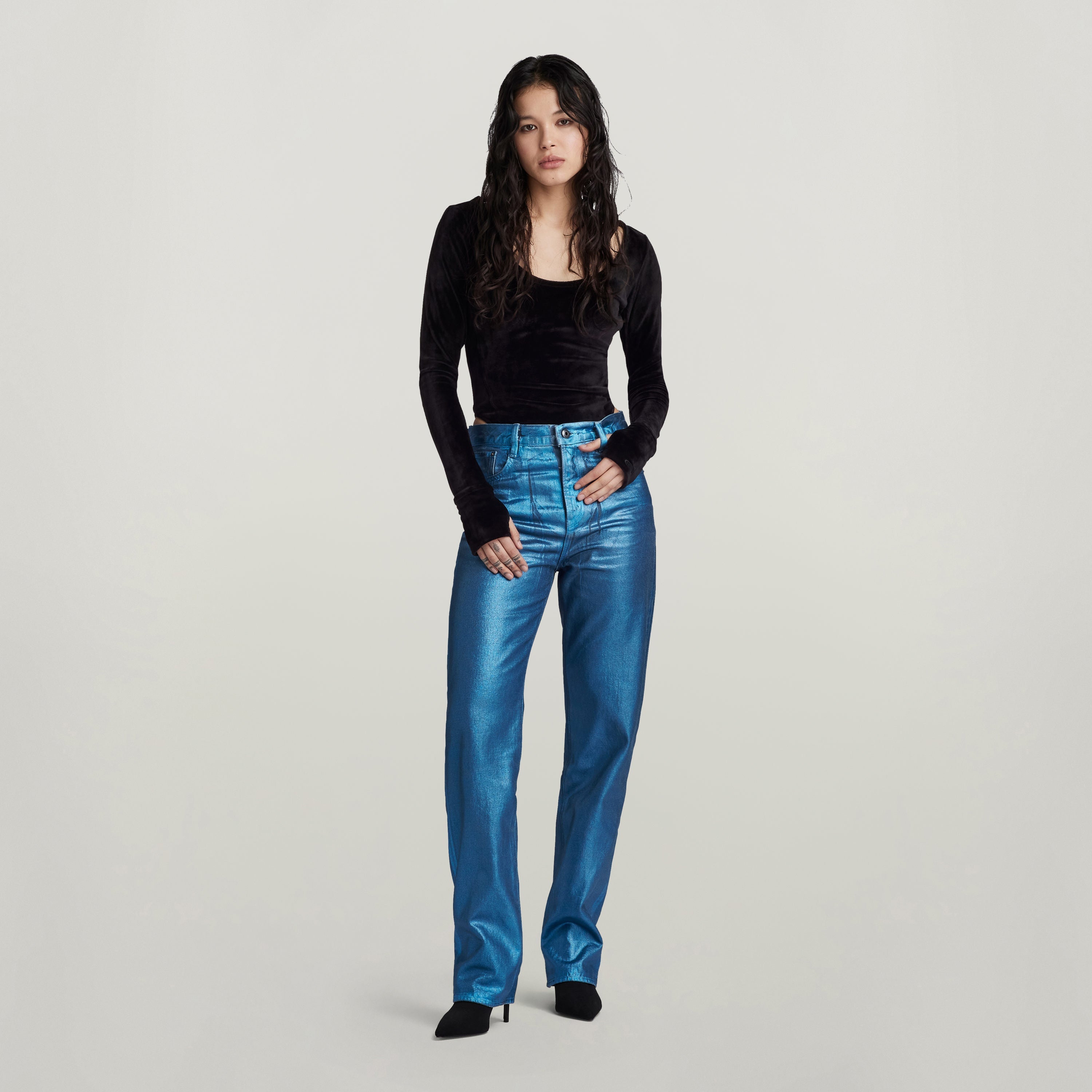 Mujer usando jeans Viktoria high straight en color azul brillante, combinados con una blusa negra de manga larga.