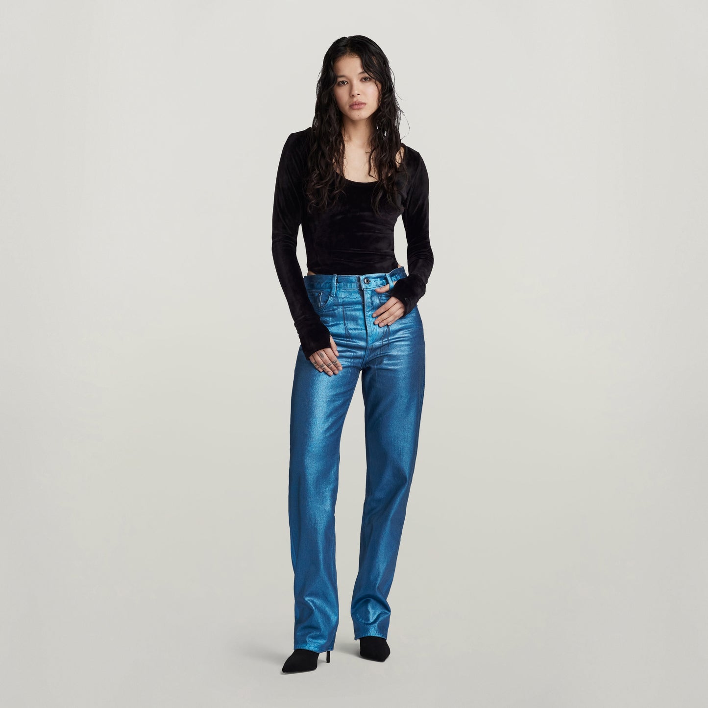 Mujer usando jeans Viktoria high straight en color azul brillante, combinados con una blusa negra de manga larga.