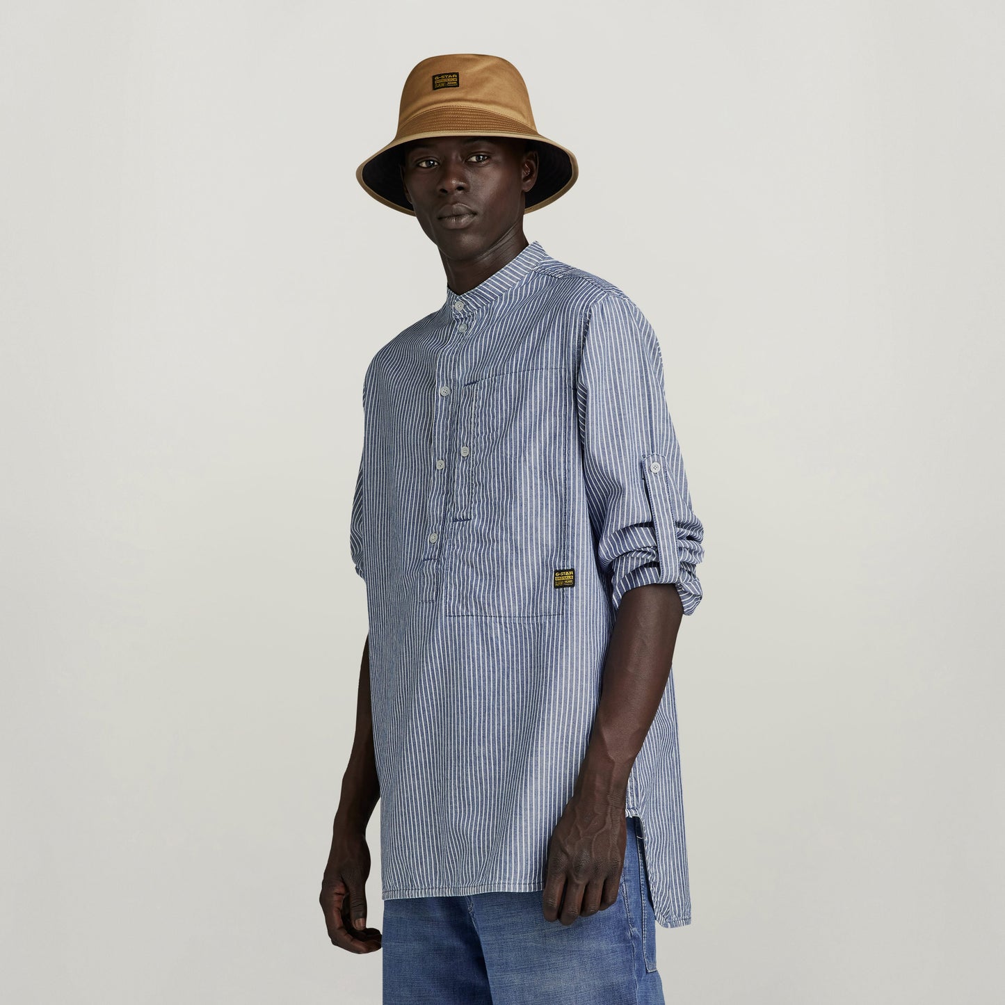 Modelo usando la camisa G4A half placket con diseño de rayas Sun Faded Deck Stripe y sombrero.