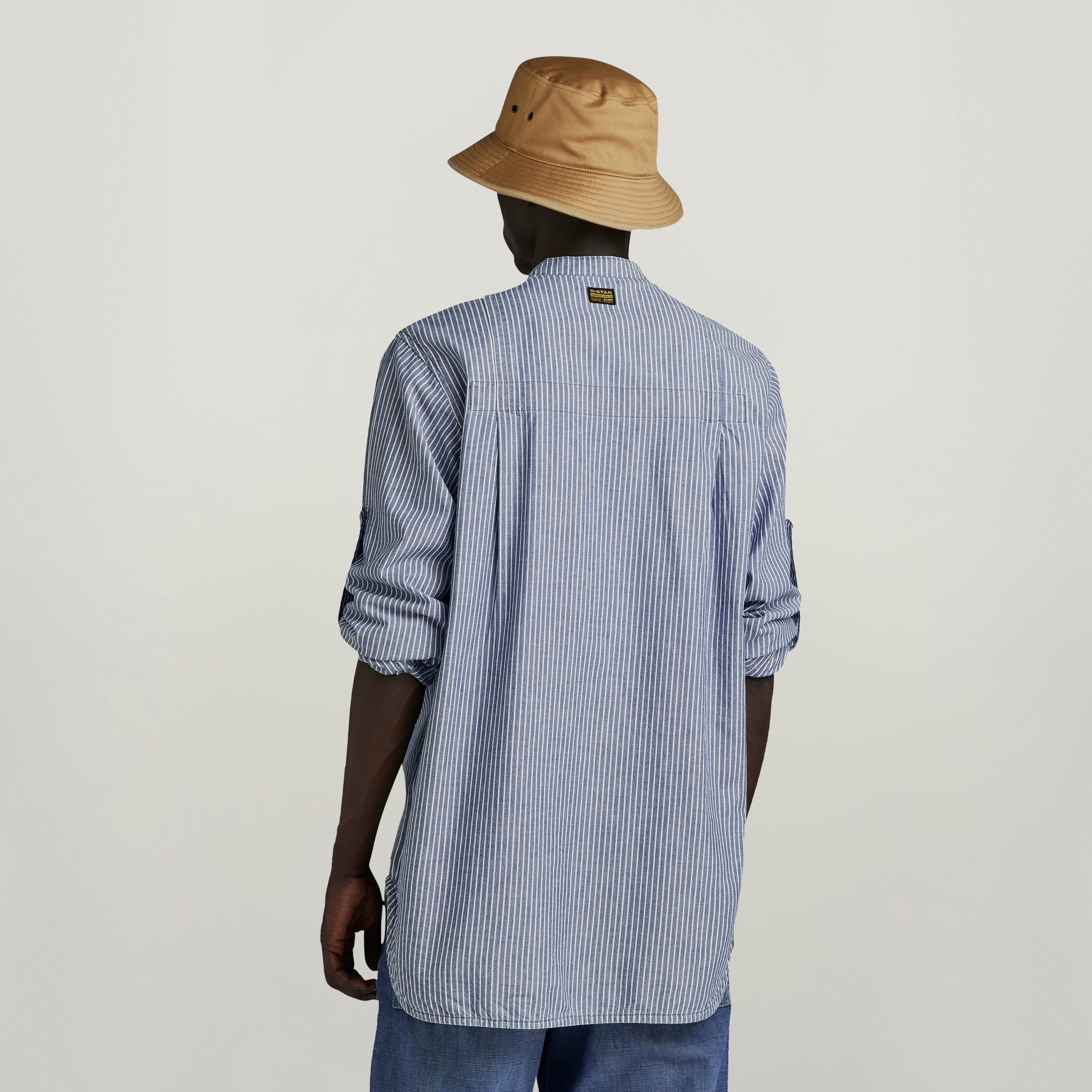 Camisa G4A Half Placket Relaxed de rayas, vista trasera con sombrero, estilo casual y relajado.
