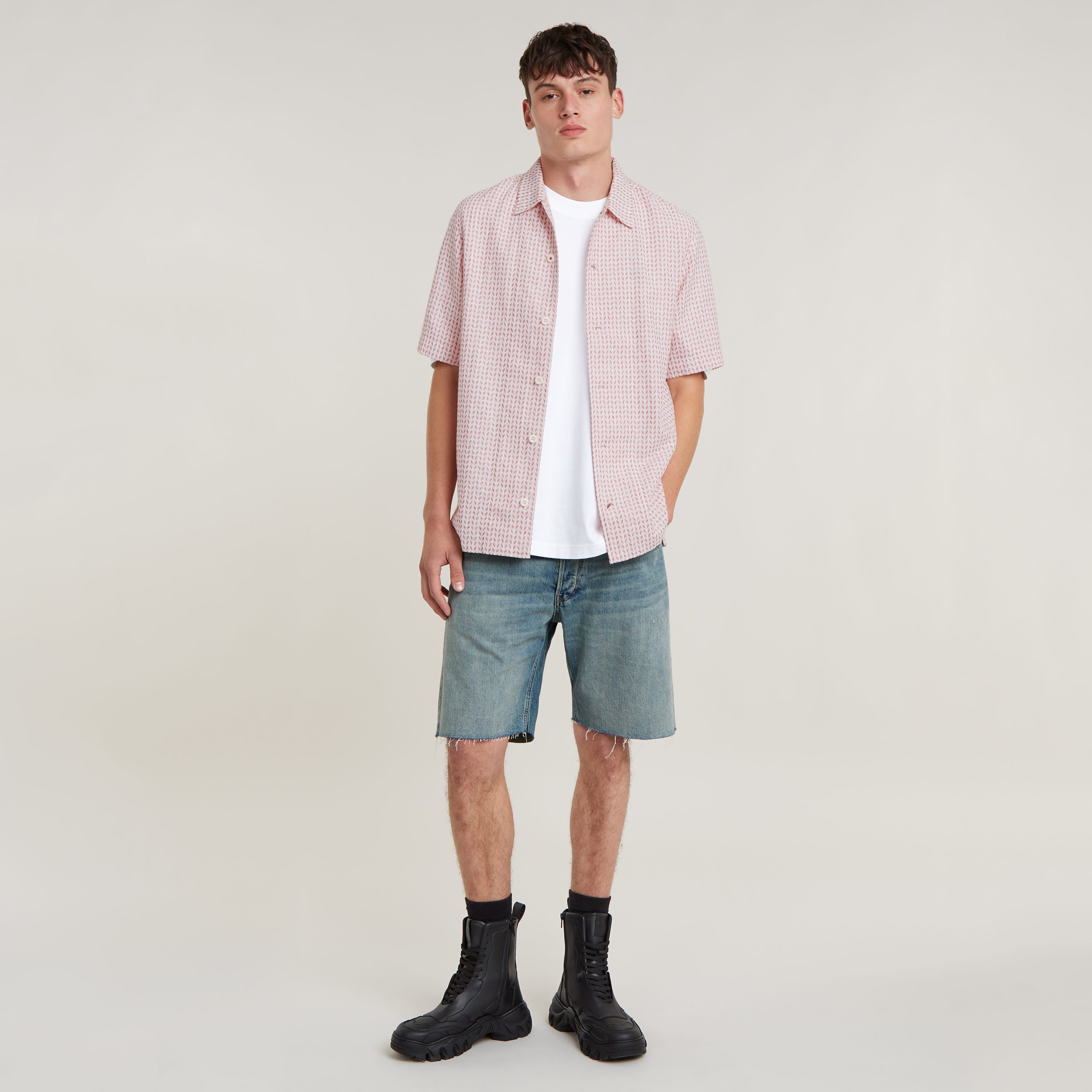 Modelo vistiendo camisa resort de corte recto con pantalones cortos y botas, fondo neutro.