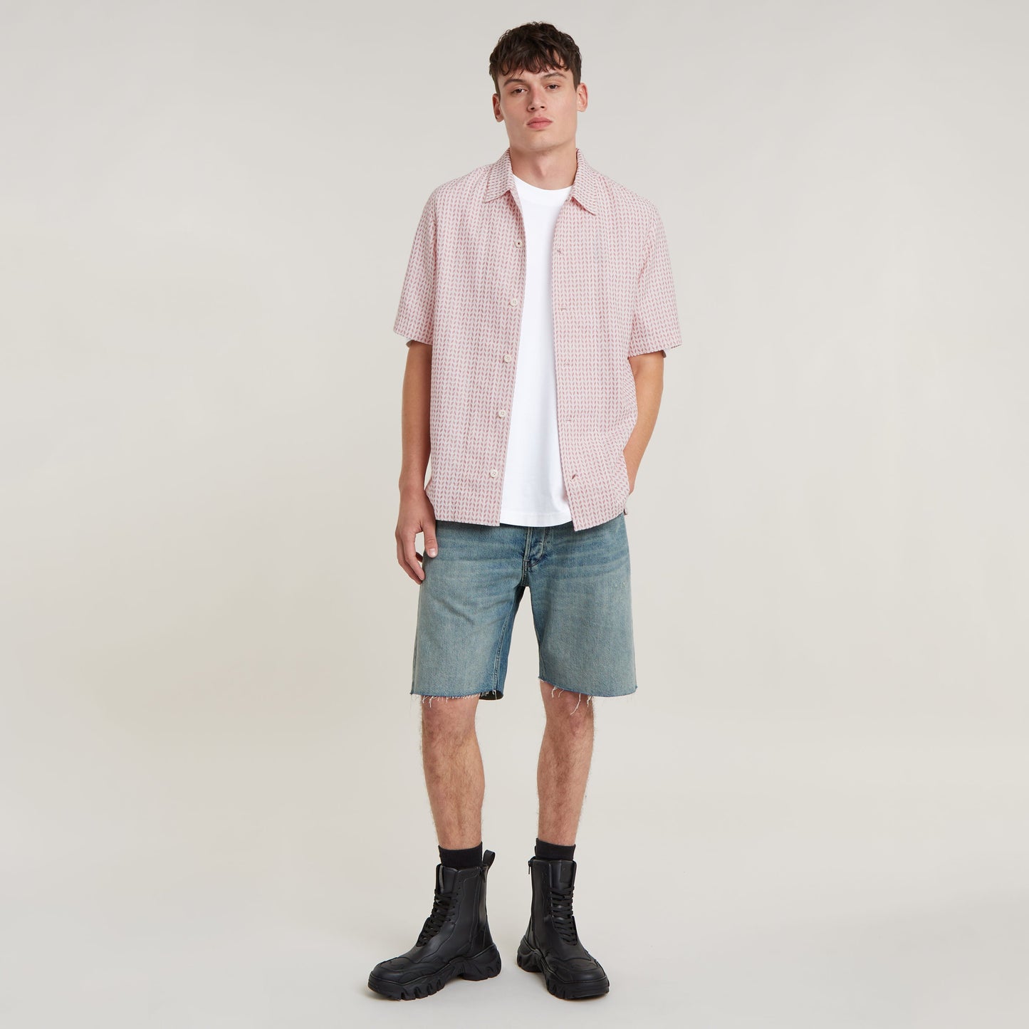 Modelo vistiendo camisa resort de corte recto con pantalones cortos y botas, fondo neutro.