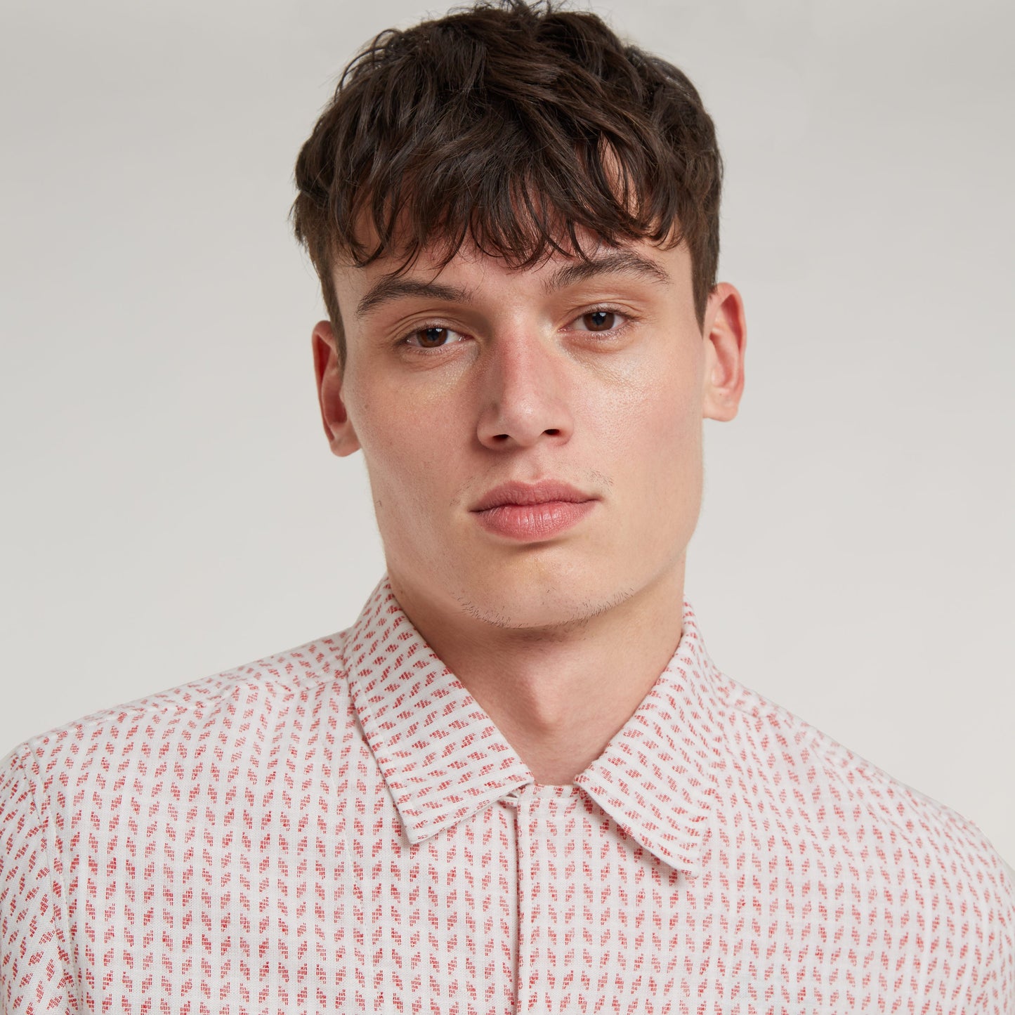 Camisa Resort de corte recto en modelo masculino, con diseño de cuello plano y patrón de colores en fondo claro.