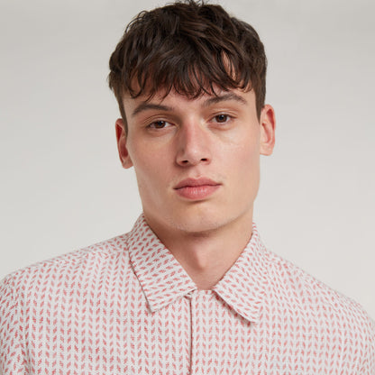 Camisa Resort de corte recto en modelo masculino, con diseño de cuello plano y patrón de colores en fondo claro.