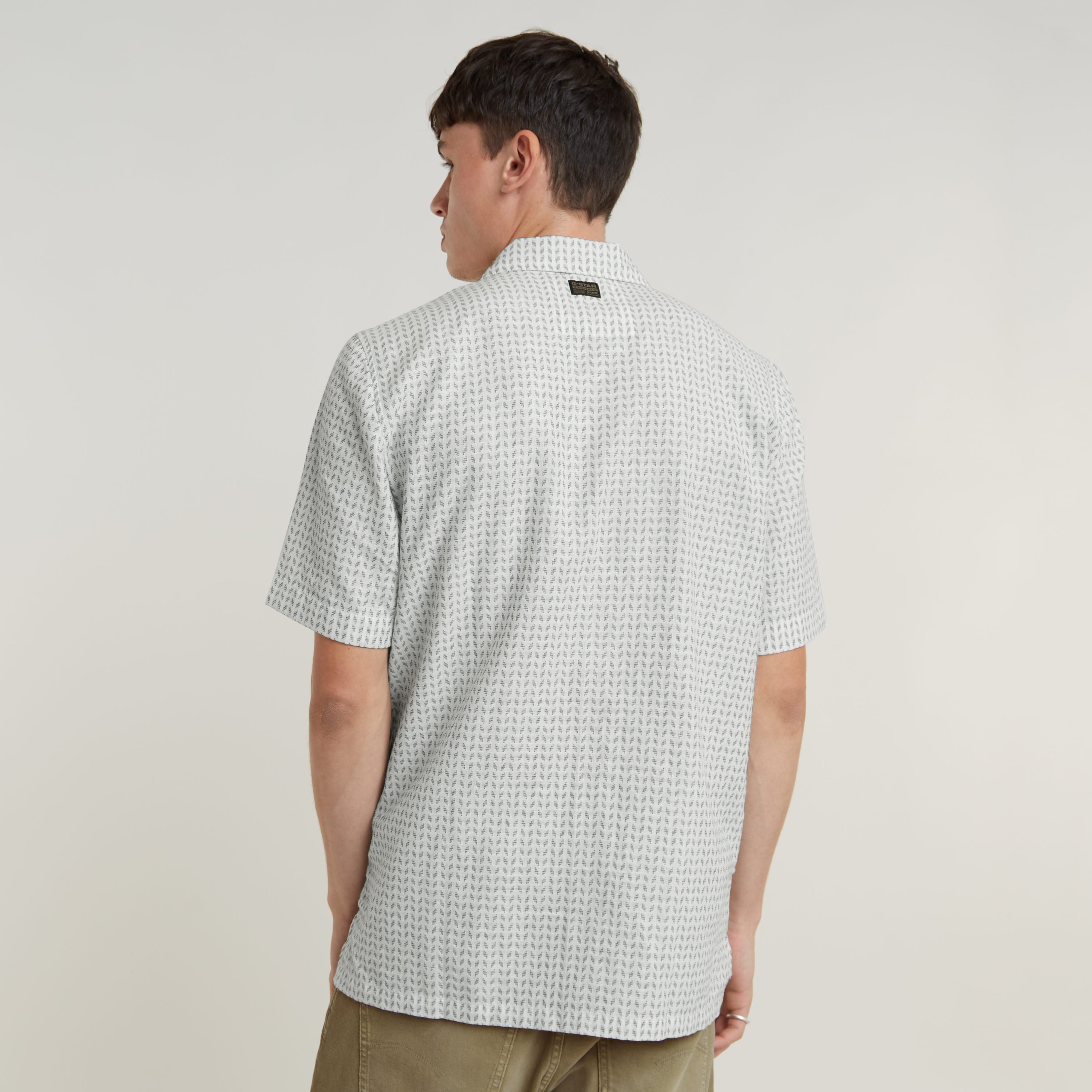 Modelo vistiendo una camisa Resort de corte recto, vista posterior, con cuello plano y diseño moderno.