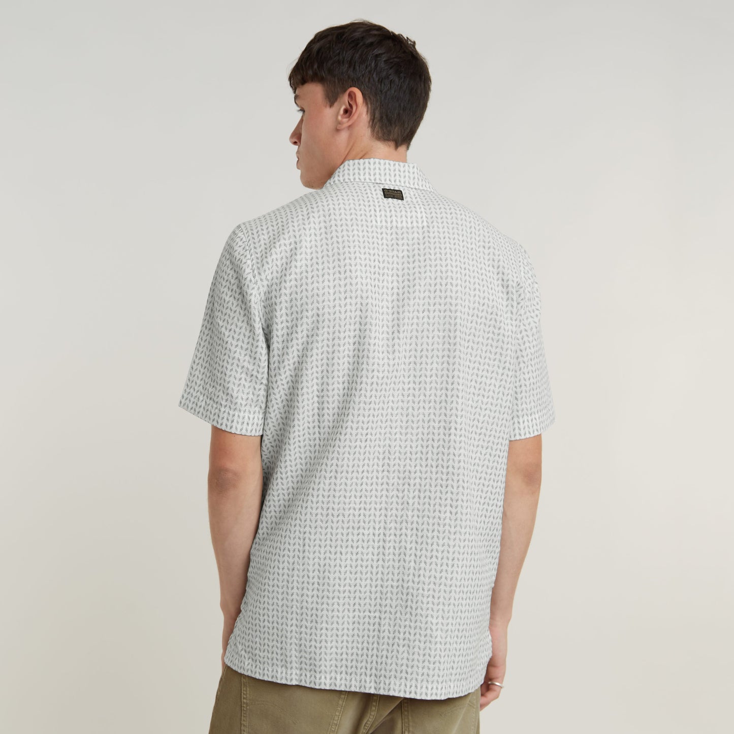 Modelo vistiendo una camisa Resort de corte recto, vista posterior, con cuello plano y diseño moderno.