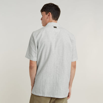 Modelo vistiendo una camisa Resort de corte recto, vista posterior, con cuello plano y diseño moderno.