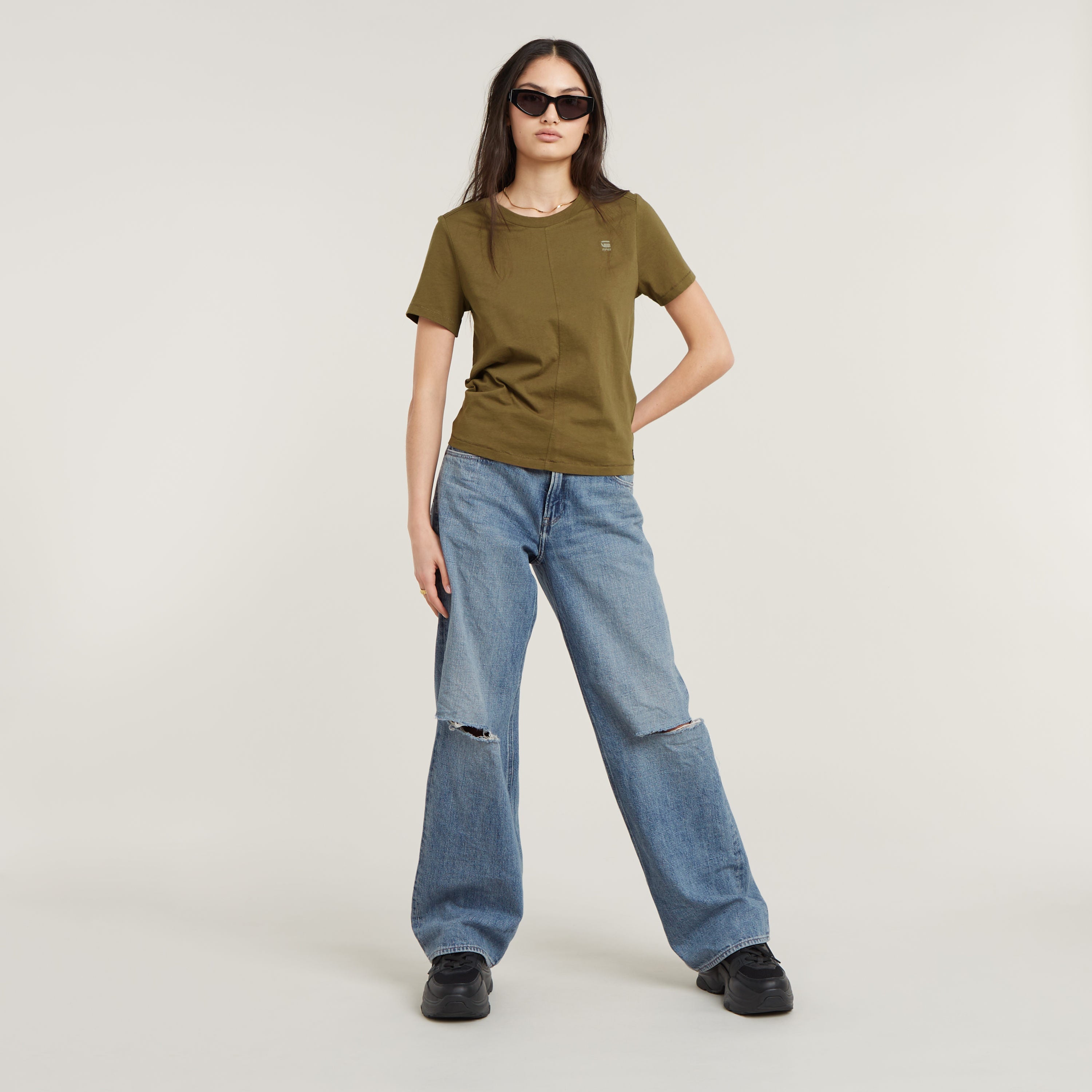 Modelo luciendo un eco-friendly front seam top verde con jeans amplios y gafas de sol.