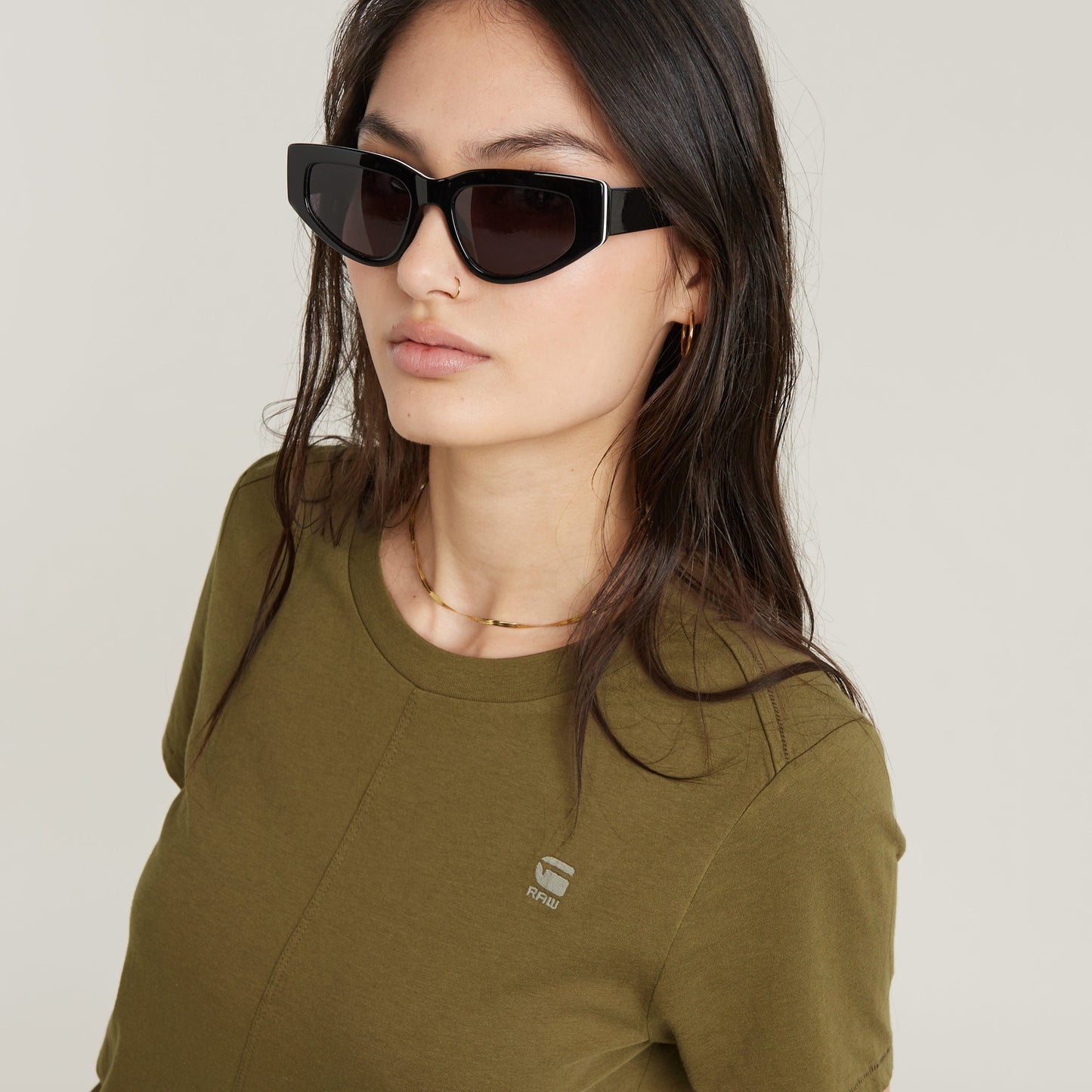 Model wearing eco-friendly front seam top in green with stylish black sunglasses.