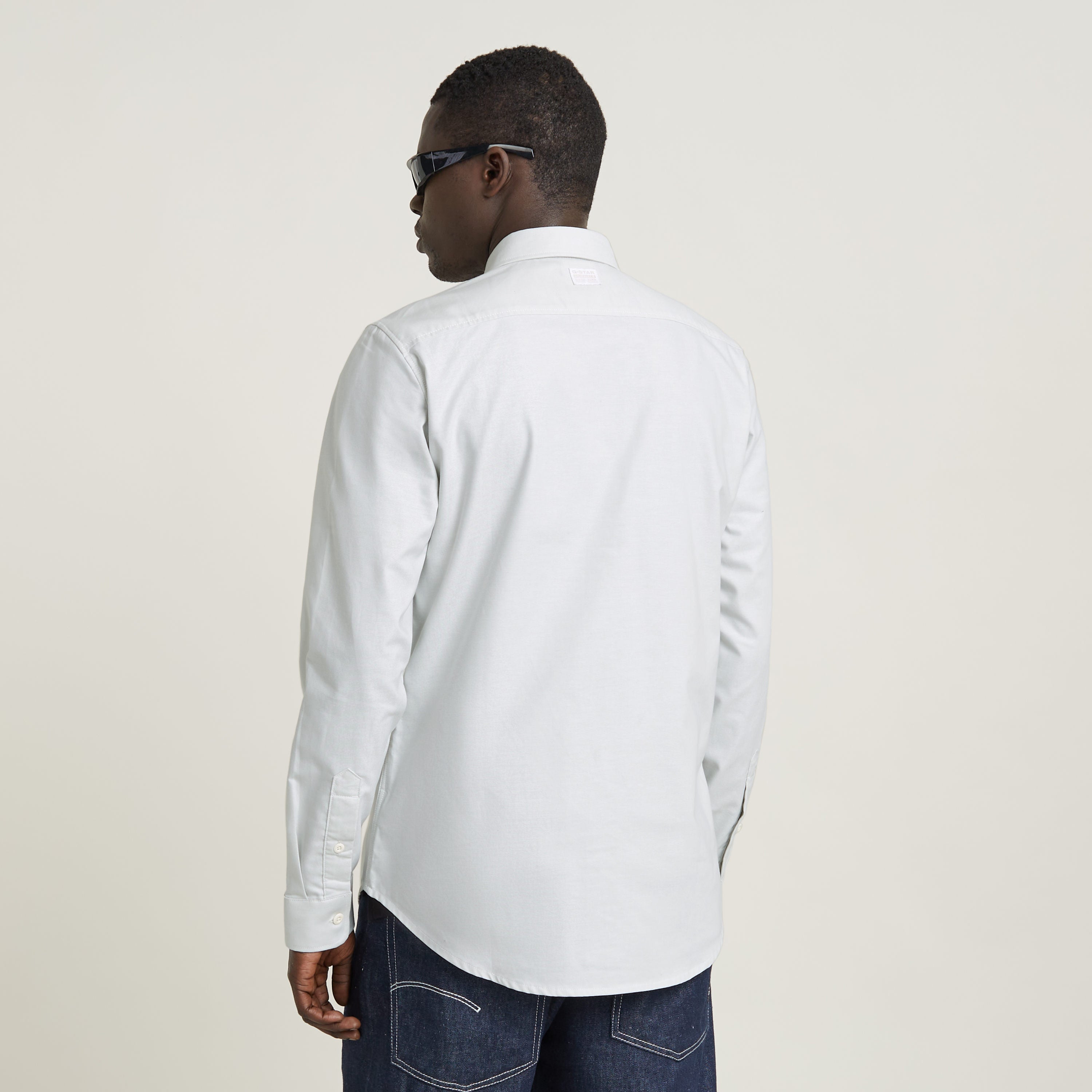 Hombre vistiendo la camisa Marine Slim ajuste de algodón en color claro, vista trasera con detalles en los puños.