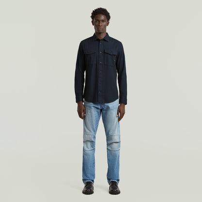 Hombre luciendo camisa marine slim azul, corte ajustado y bajo redondeado, en fondo claro.